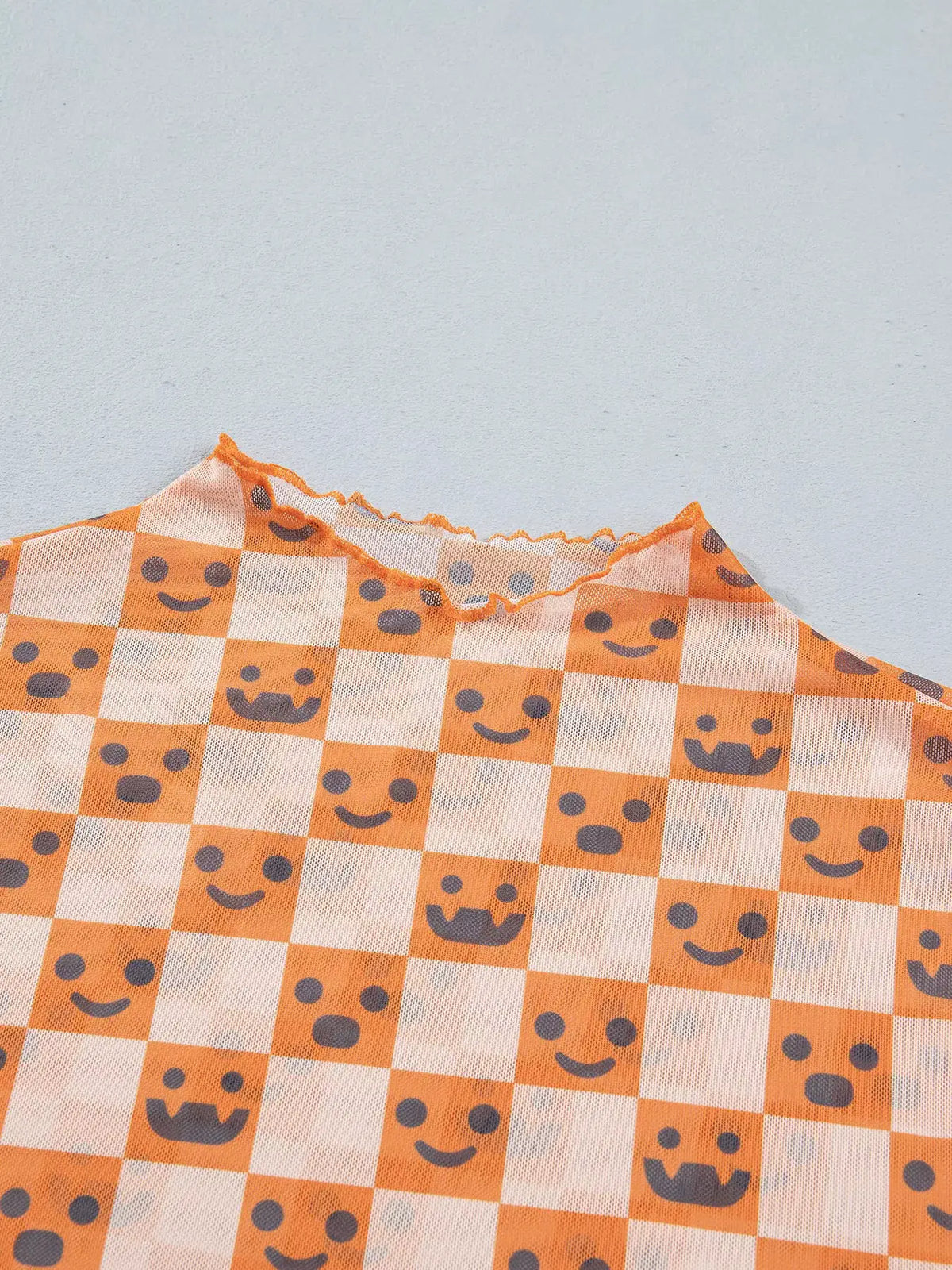 Abstract Halloween pattern long-sleeve mock-neck blouse in orange and white checker squares with gray smiley faces