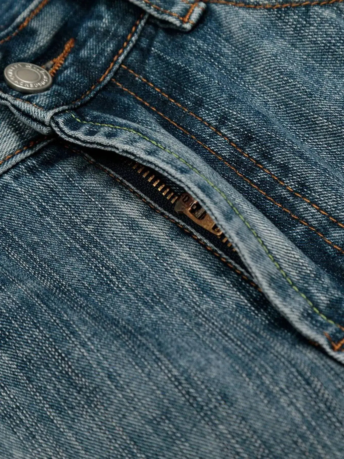 Mens wide-leg washed denim shorts; close-up of blue denim fabric with zipper and orange stitching