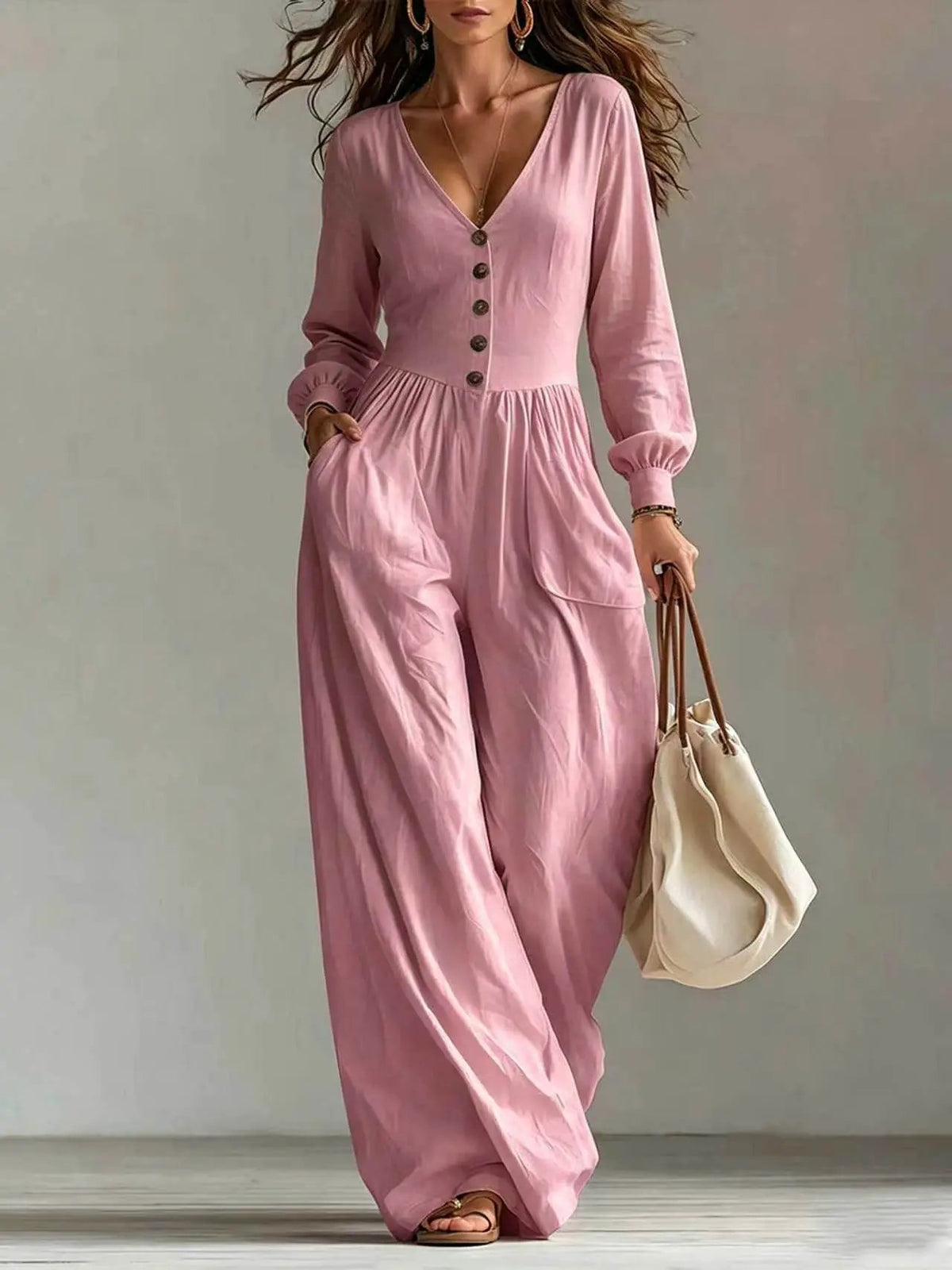 Women's pink V-neck jumpsuit with long sleeves, button front and pockets, wide-leg pants.