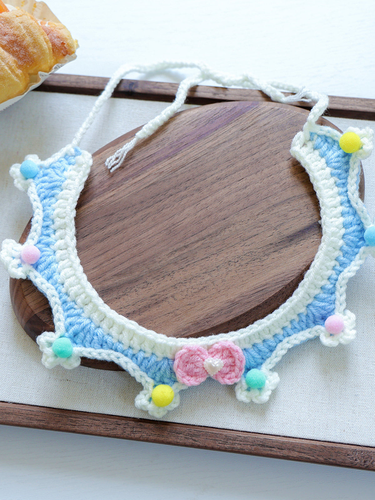 Contrast Pet Scarf, crocheted in white and light blue with pastel pom-poms and a pink heart charm