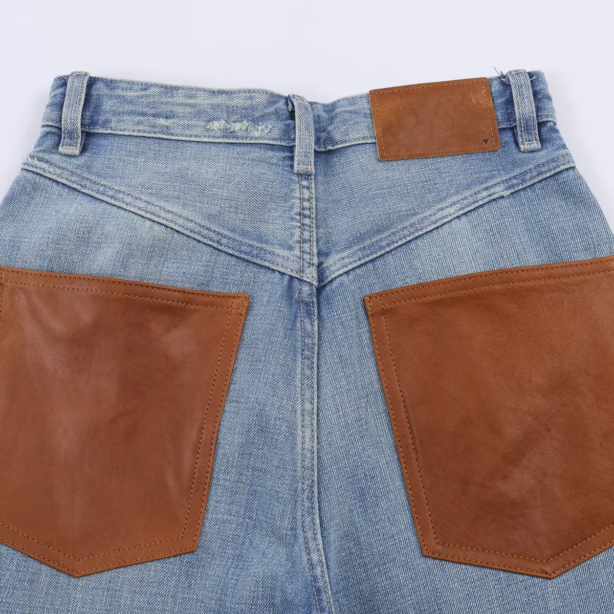 High-waisted wide-leg jeans with blue denim and two brown leather back pockets.