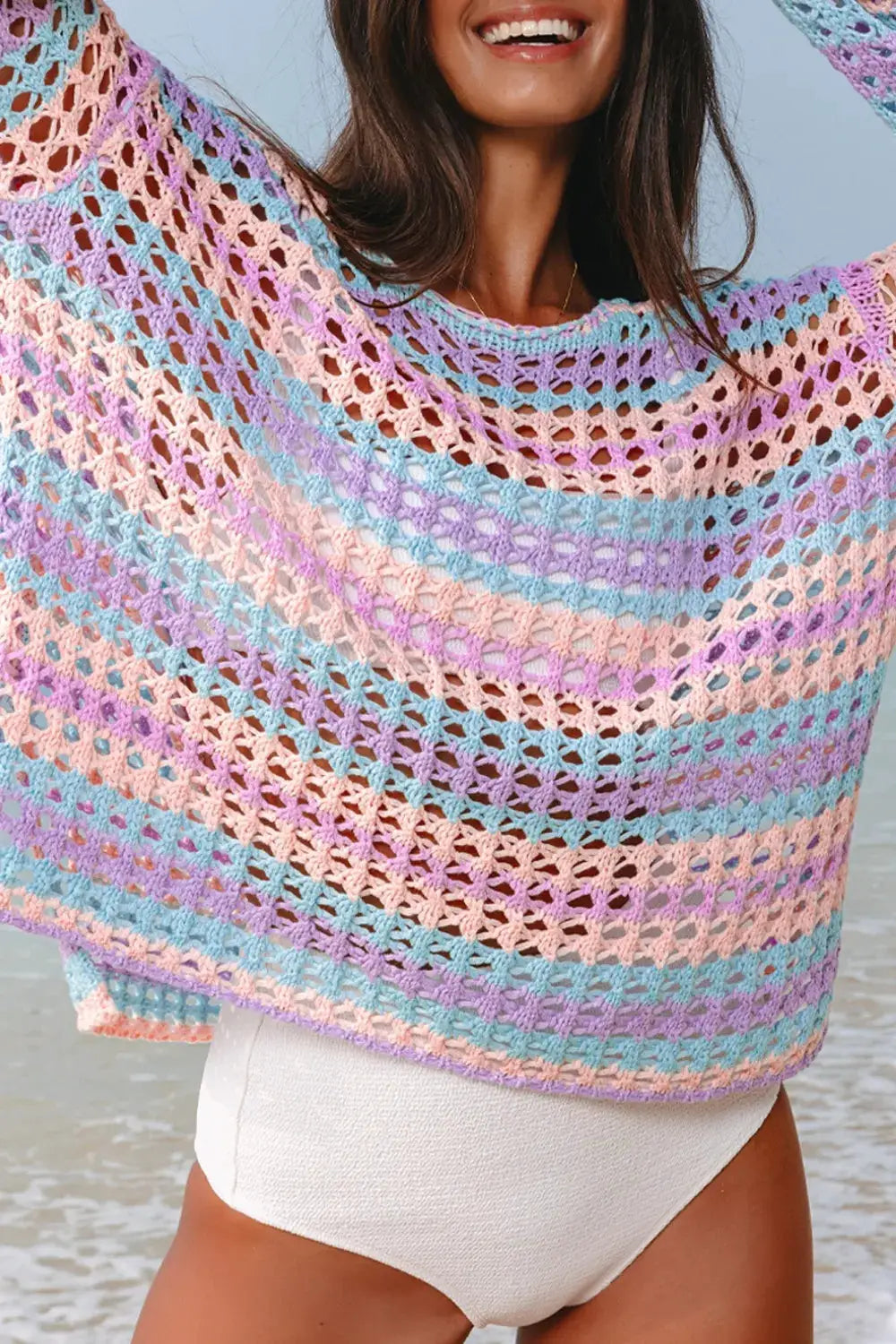 Striped pastel openwork beach cover-up poncho with round neck and side slits; crochet knit over white bikini bottom