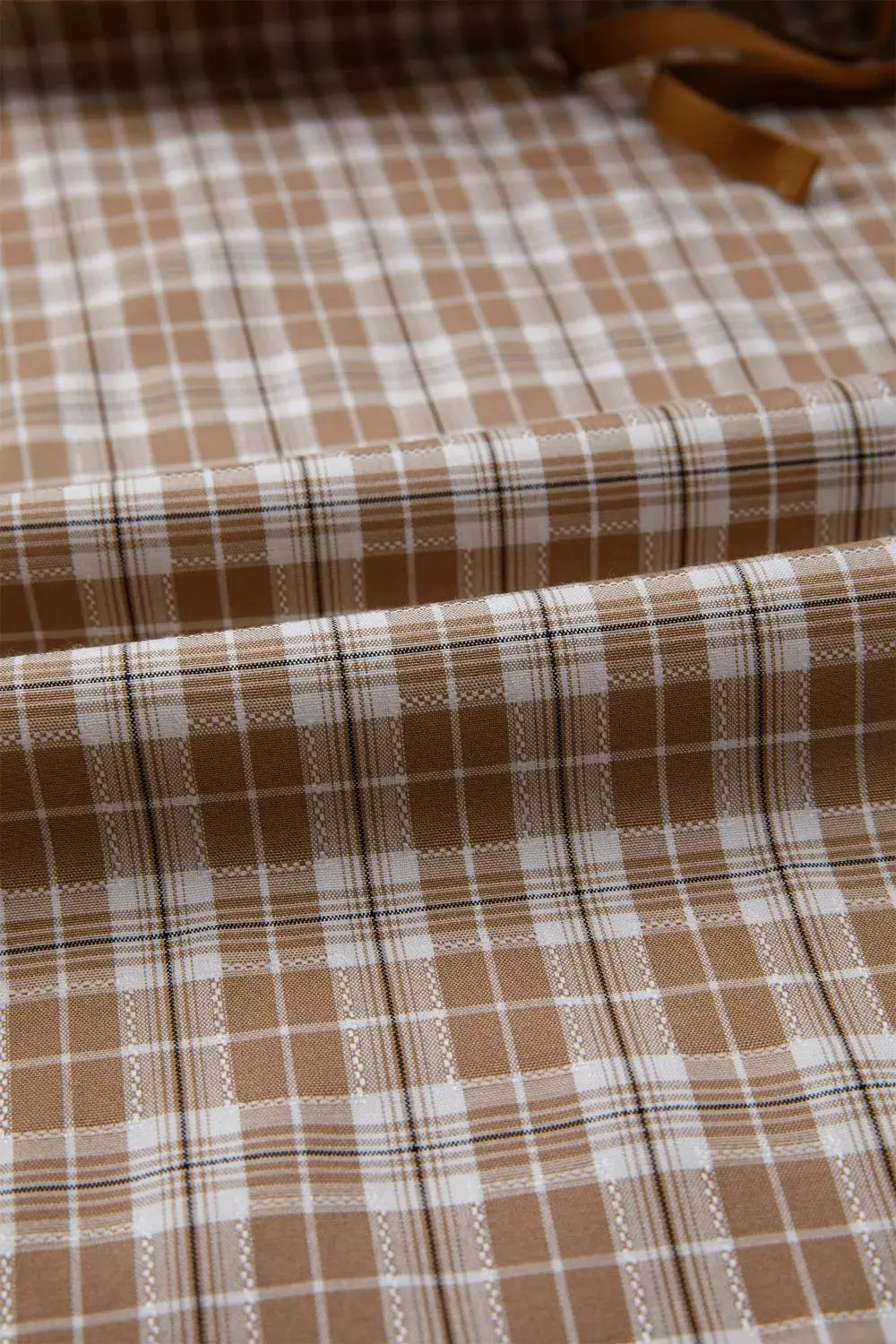 Plaid print tie-detail casual pants fabric in tan and white, close-up view