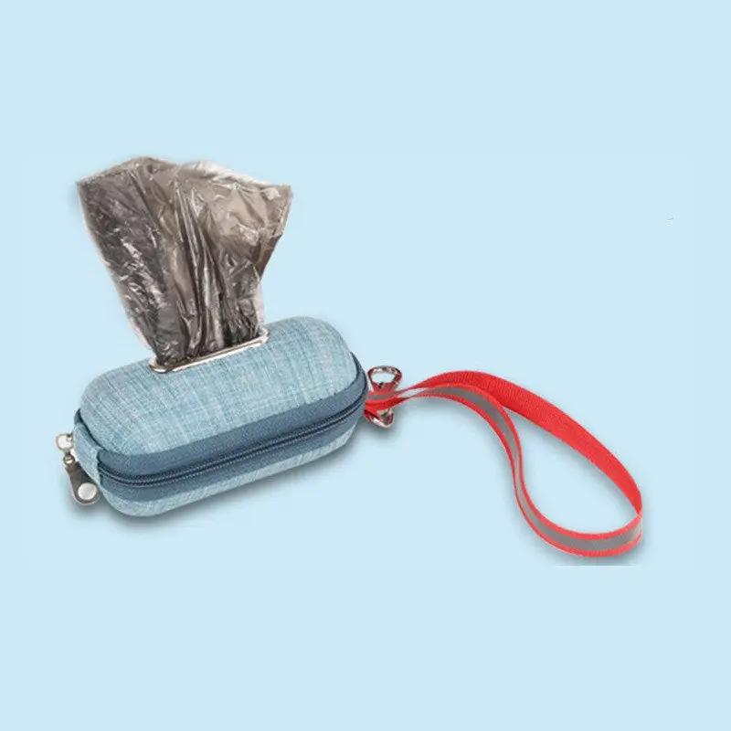 Portable dog poop bag dispenser in blue denim with red strap and clip.