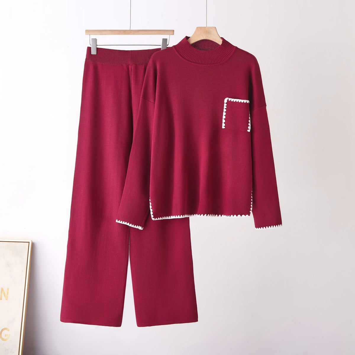 Two-piece burgundy knit set with half-high neck top and straight-leg pants, white zigzag trim on pocket and hem