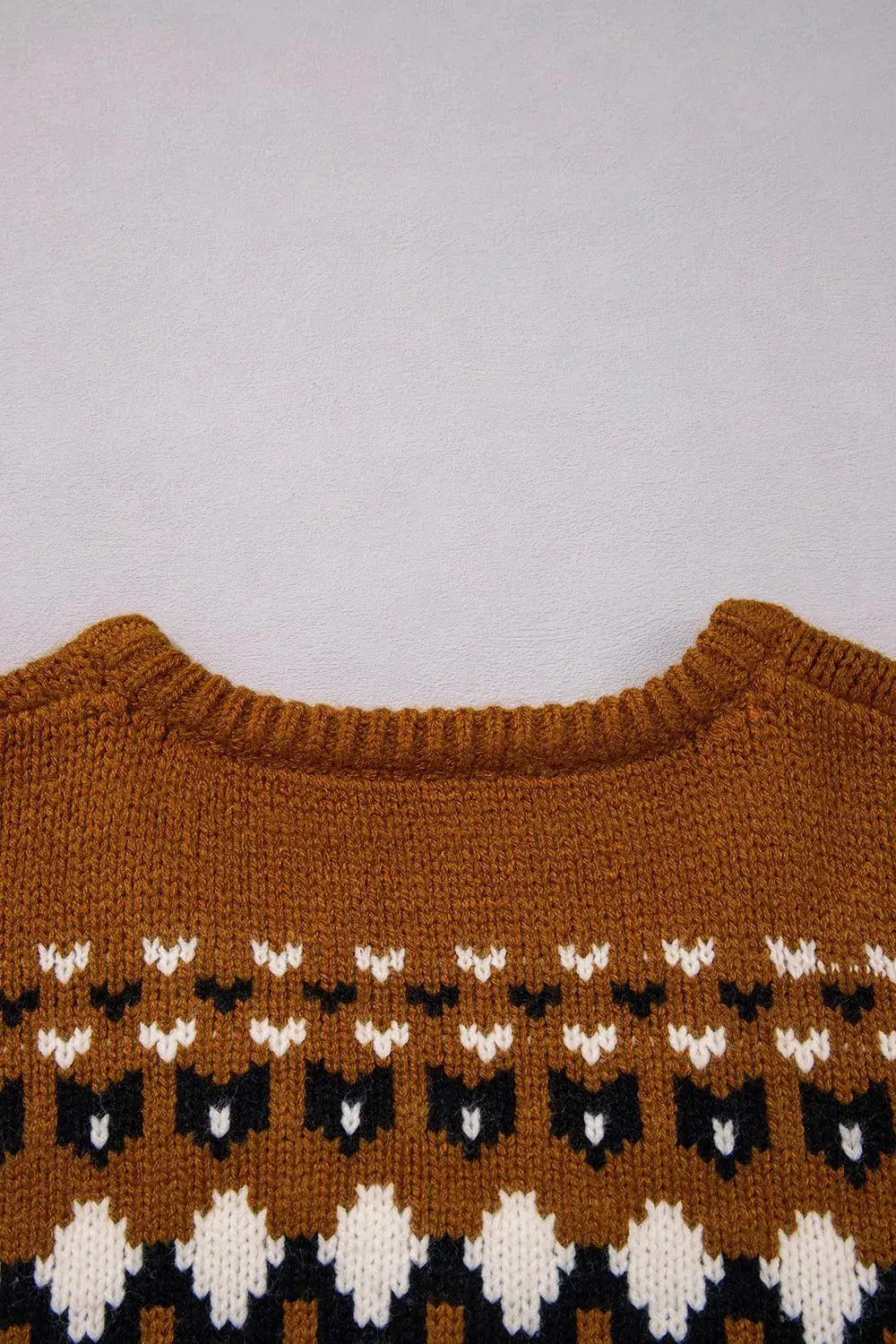 Brown knit geometric sweater with white and black pattern.