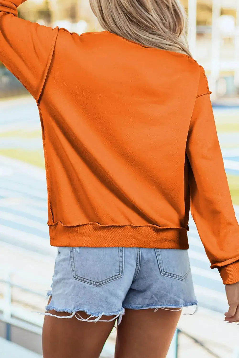 Spooky Season Mock Neck Reversible Halloween Sweatshirt in orange; back view with ribbed hem, shown with denim shorts (2 items)