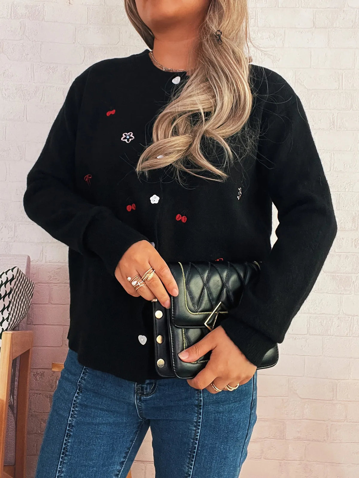 Ribbed black knit cardigan with button-front closure and subtle floral embroidery.