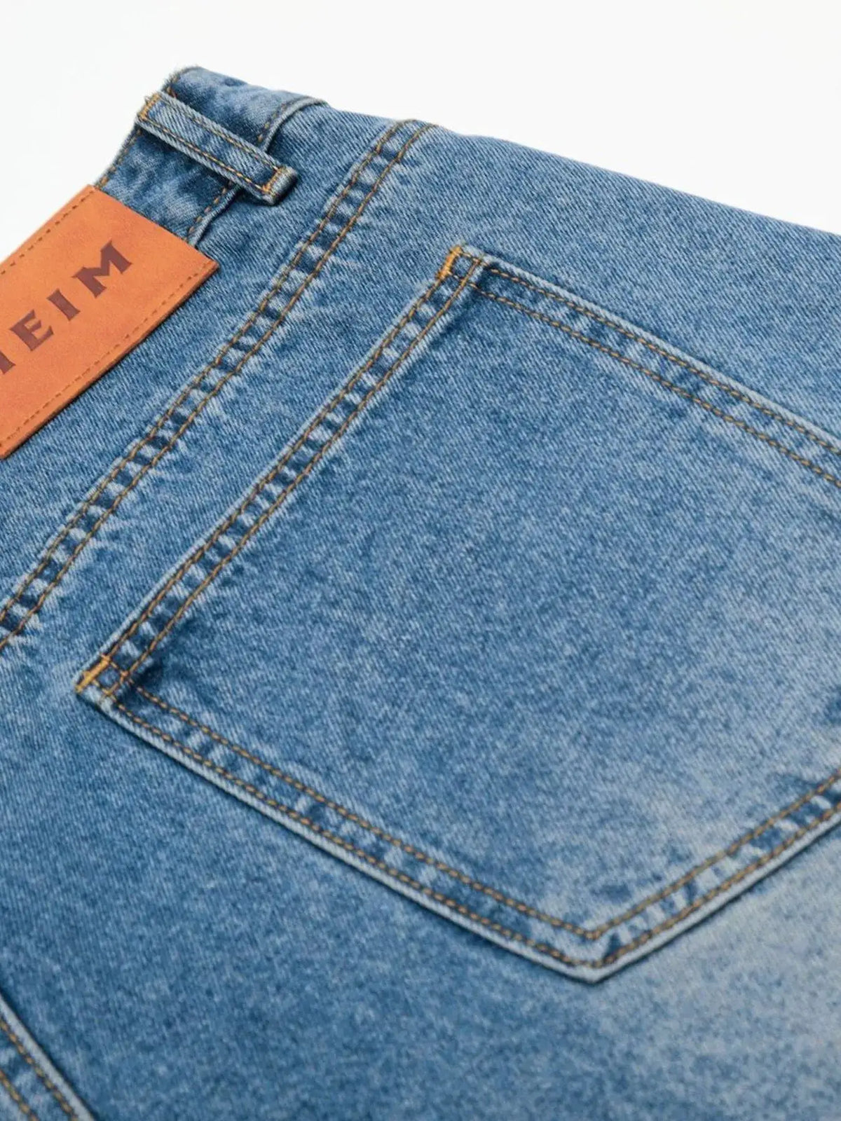 Men's Relaxed Fit Wide Leg Washed Cotton Denim Shorts; blue denim with orange patch, belt loop and yellow stitching.