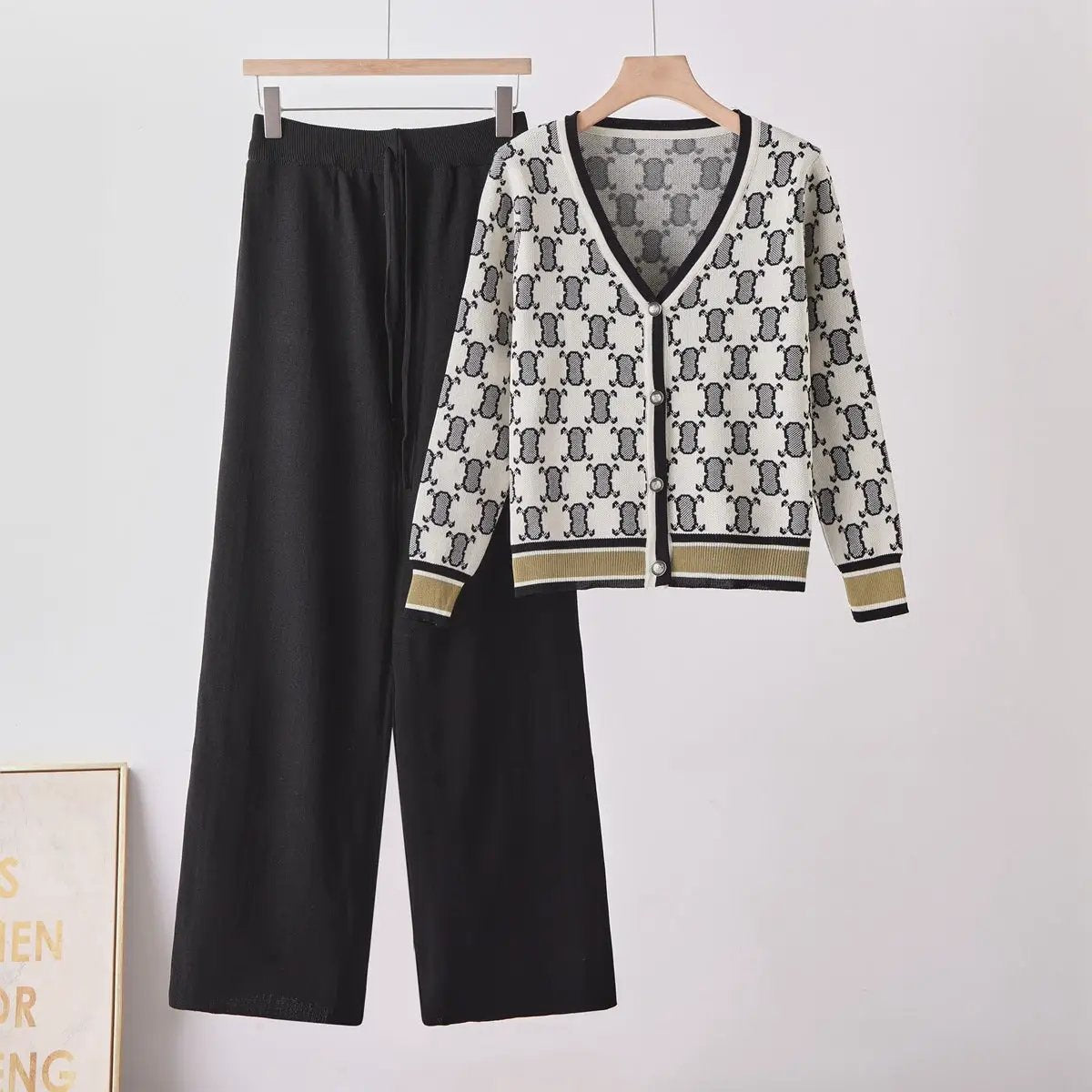 Chic two-piece knit set: cream cardigan with black geometric pattern and gold trim, paired with black wide-leg pants