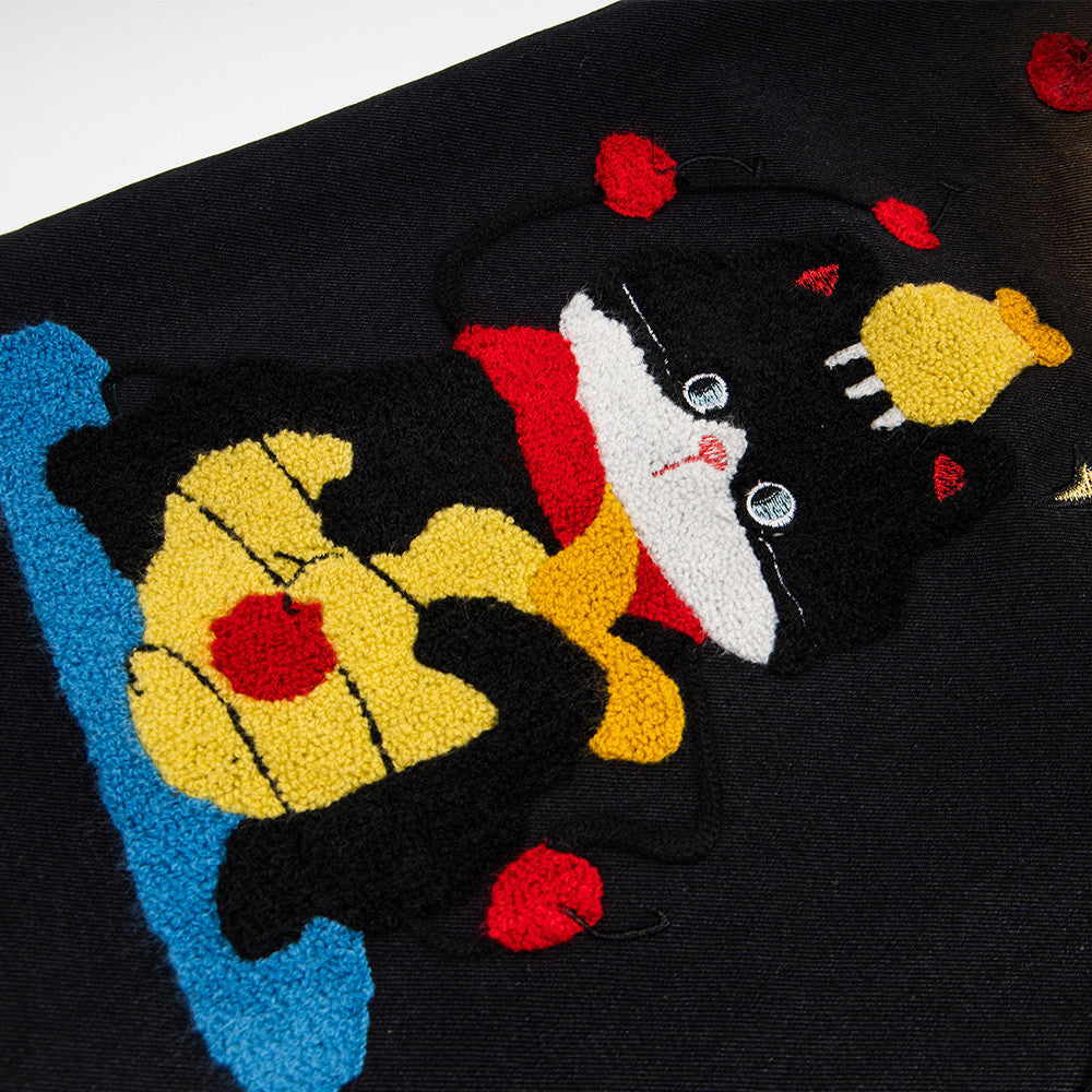 Denim shorts with cartoon embroidery patch on black fabric, street fashion style.