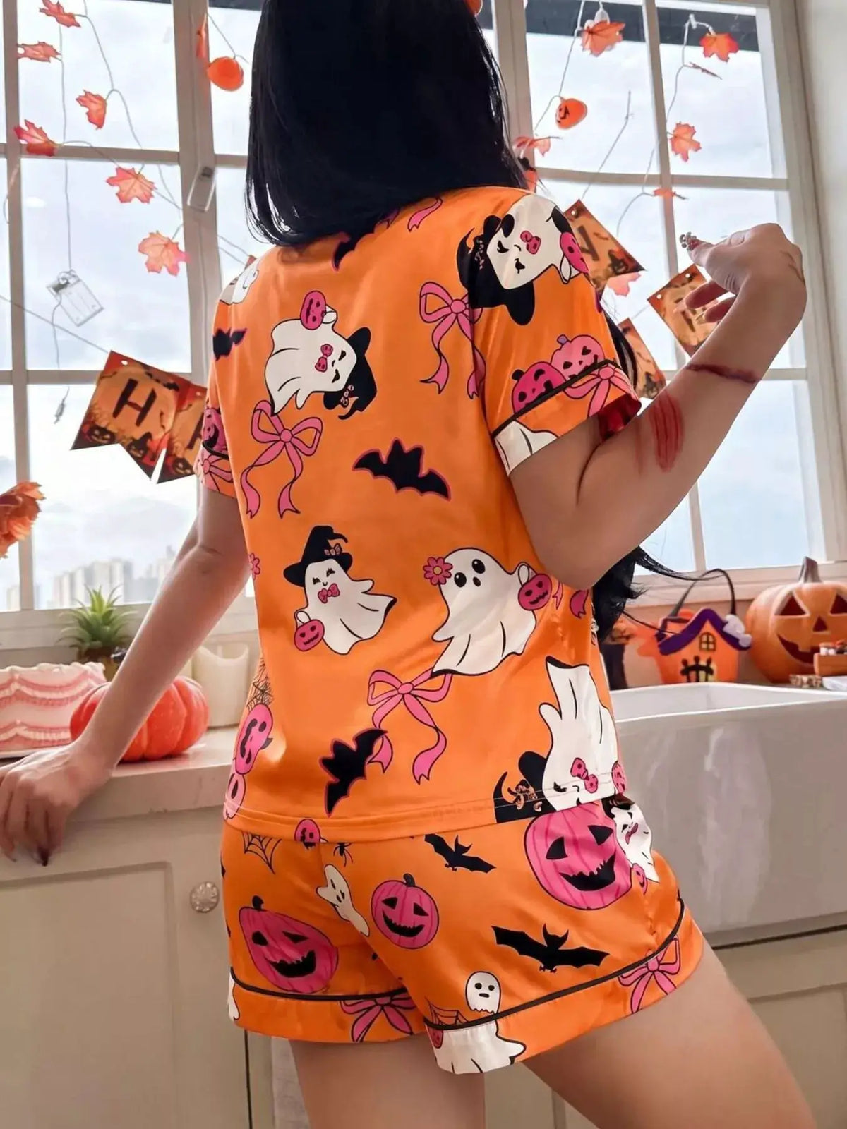 Halloween ghost-print button-down top and orange shorts lounge set, 2-piece by Trendsi; ghosts, bats, pumpkins motif.
