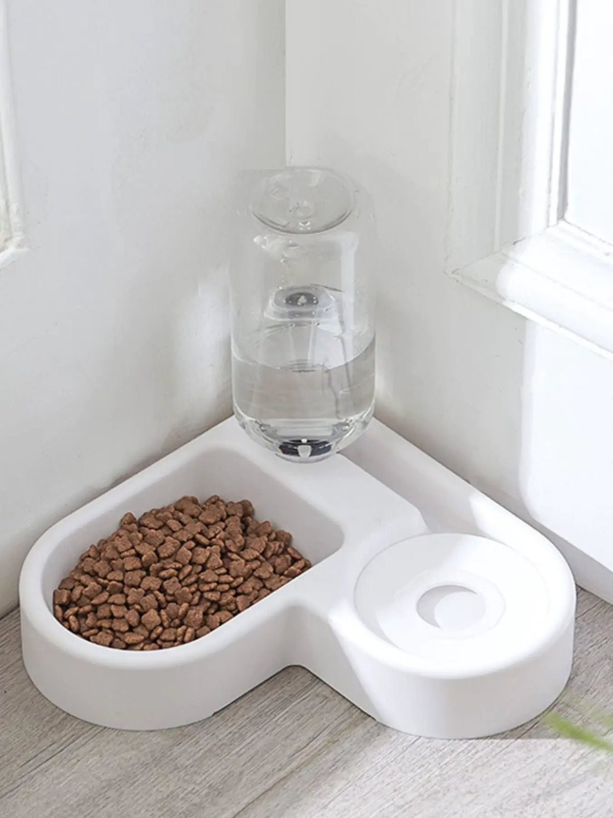 Automatic water-refilling pet bowls in white plastic with clear water bottle; kibble bowl on left.