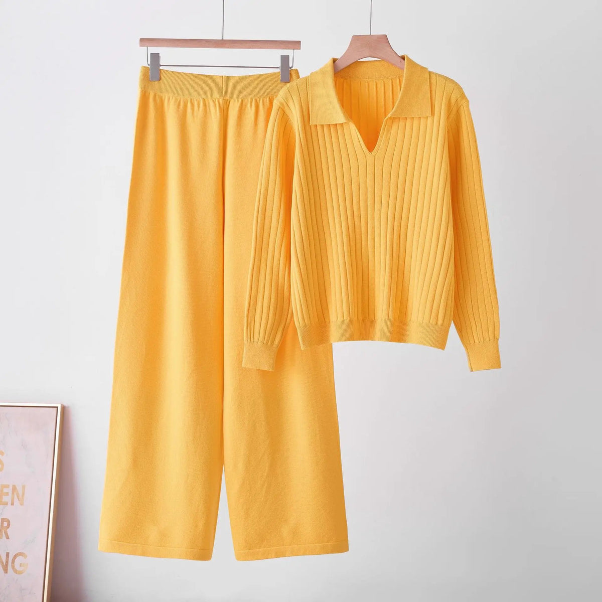 Matching women's knit polo-neck sweater set in yellow; pleated-knit top with V-neck and matching wide-leg pants.