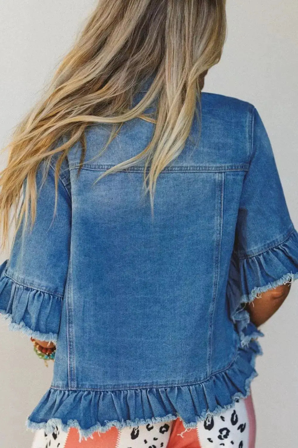 Womens denim jacket with ruffle hem and raw-edge half sleeves in blue.