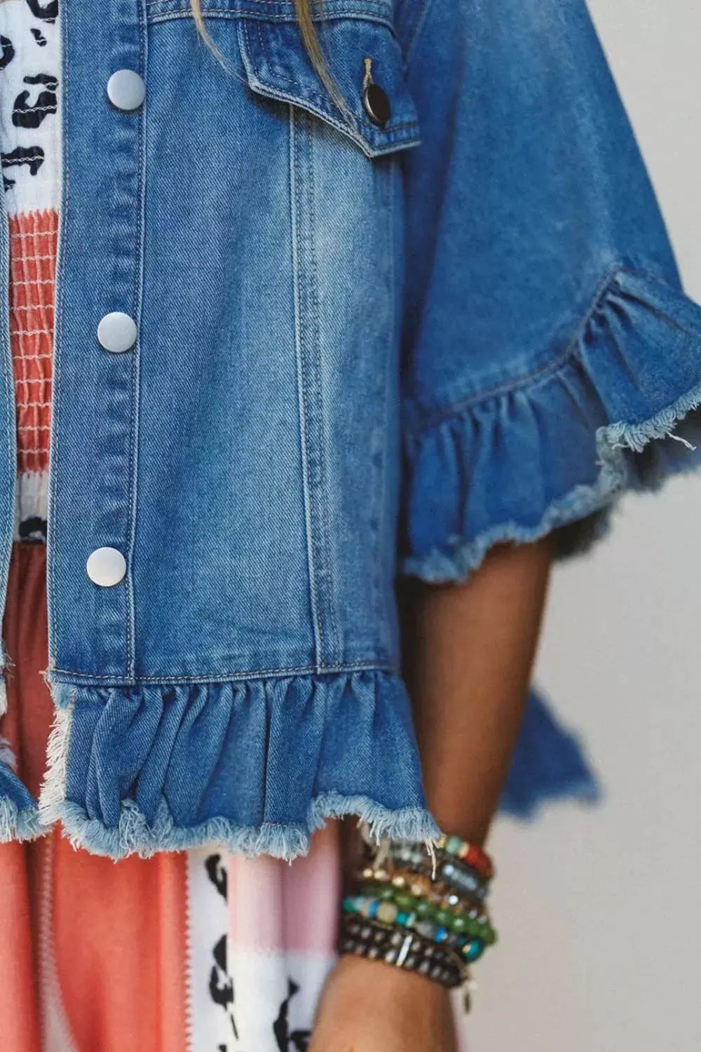 Womens blue denim jacket with ruffle hem and raw-edge trim, short puff sleeves.