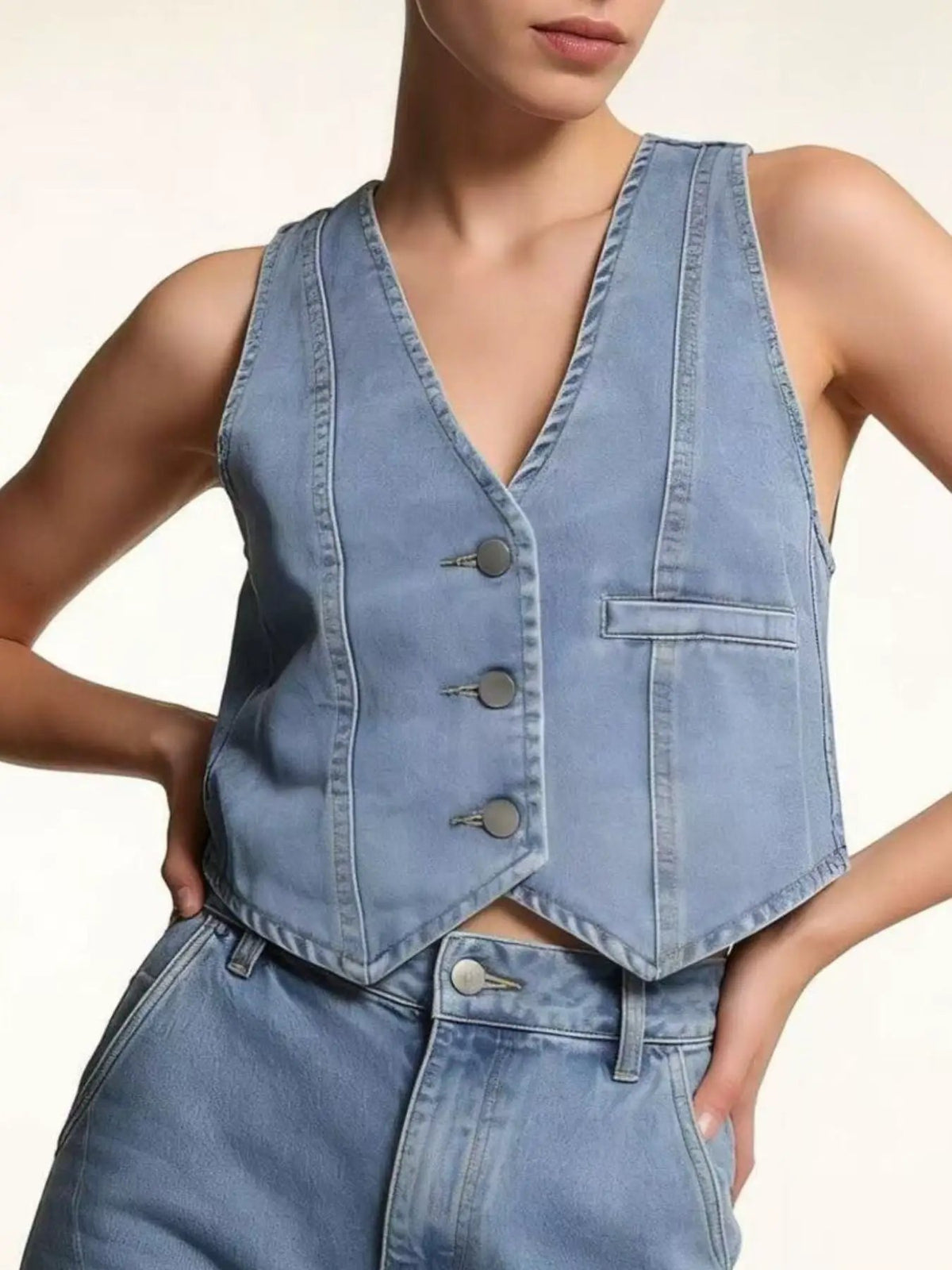 Two-piece light blue denim set: unlined button-down vest with V-neck and front pocket, with matching denim bottoms.