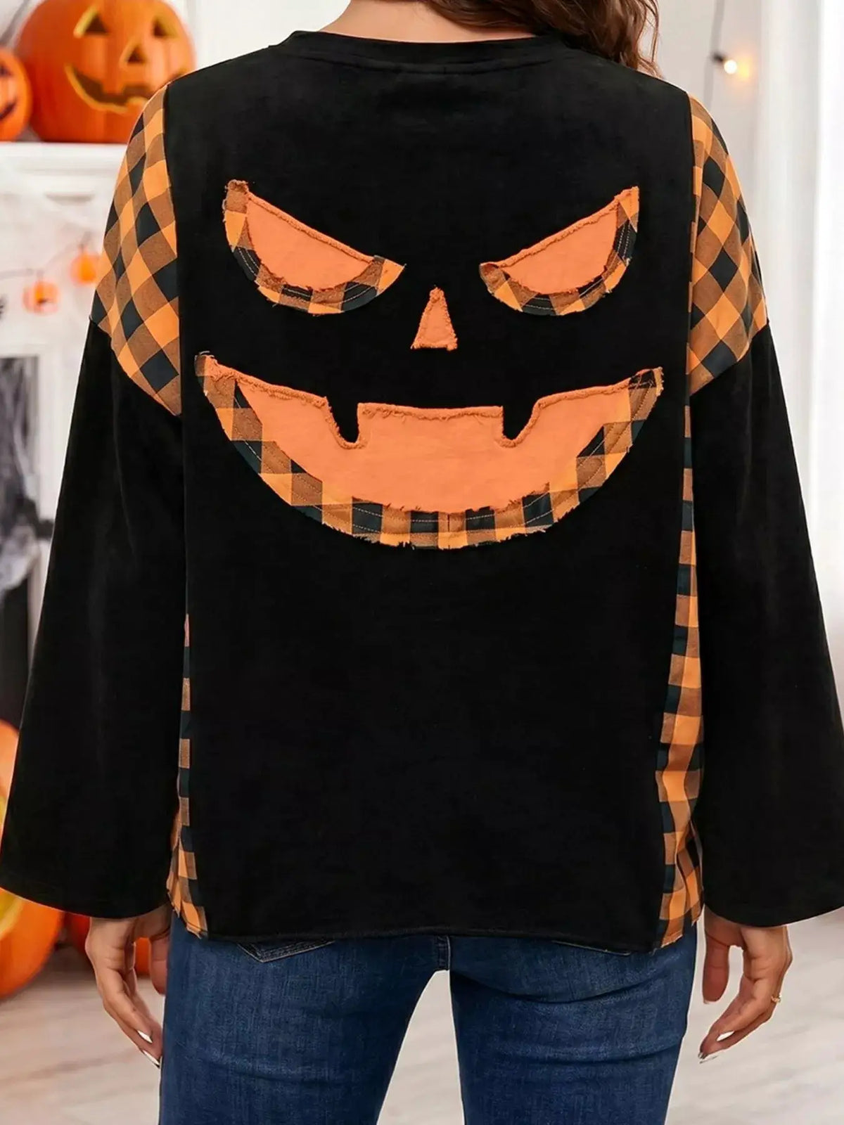 Patchwork plaid pumpkin face long sleeve top in black with orange plaid patchwork on back and sleeves.