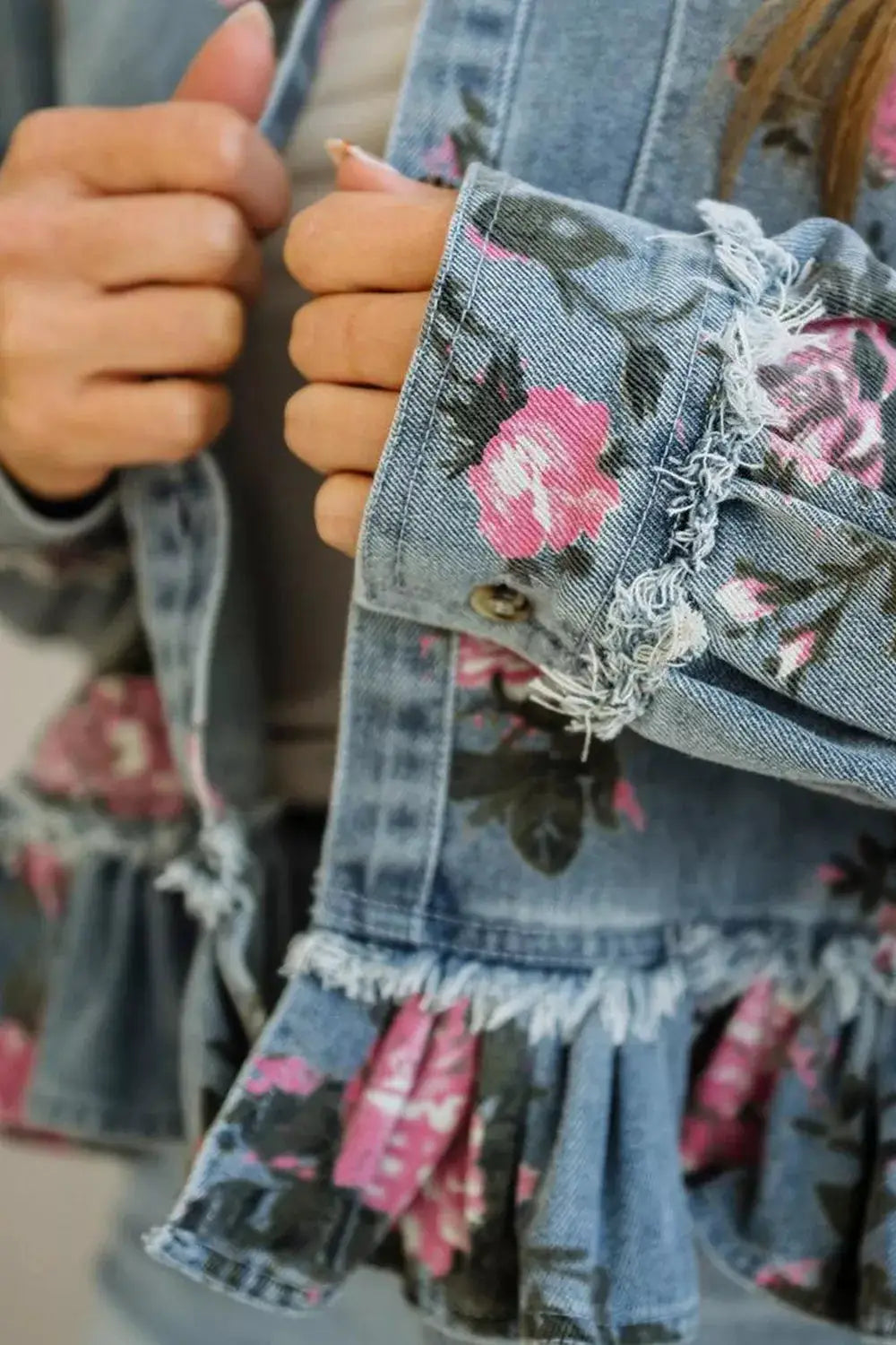 Women’s floral print denim jacket with pink blooms and a frayed, ruffled hem