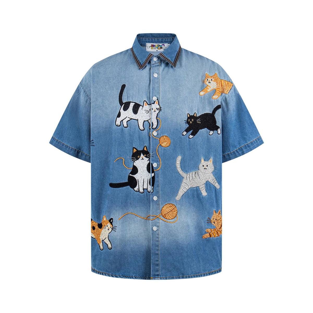 Cat-embroidered denim short-sleeve shirt in blue denim with playful cat illustrations.