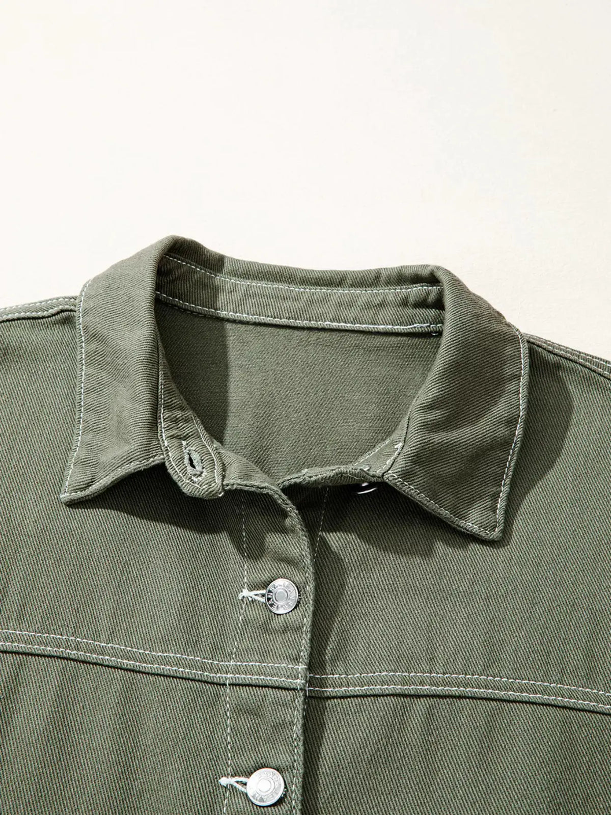 Denim jacket in olive green with metal button closure and visible white stitching