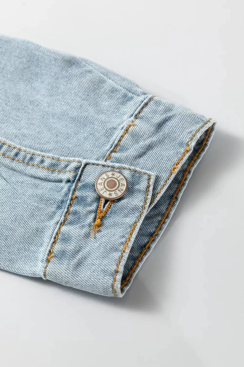 Denim jacket cuff in light wash with orange topstitching by Trendsi