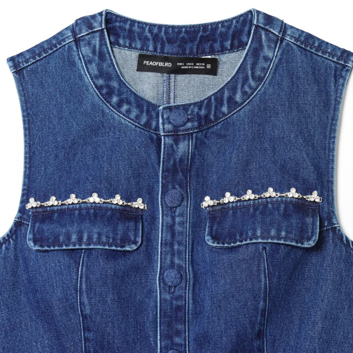 Nail drill denim vest in blue with pearl-embellished pocket flaps and front buttons.