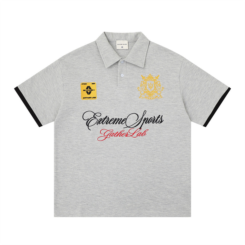 Embroidered emblem polo T-shirt in heather gray with yellow crest and patch, black sleeve trim and script text across chest