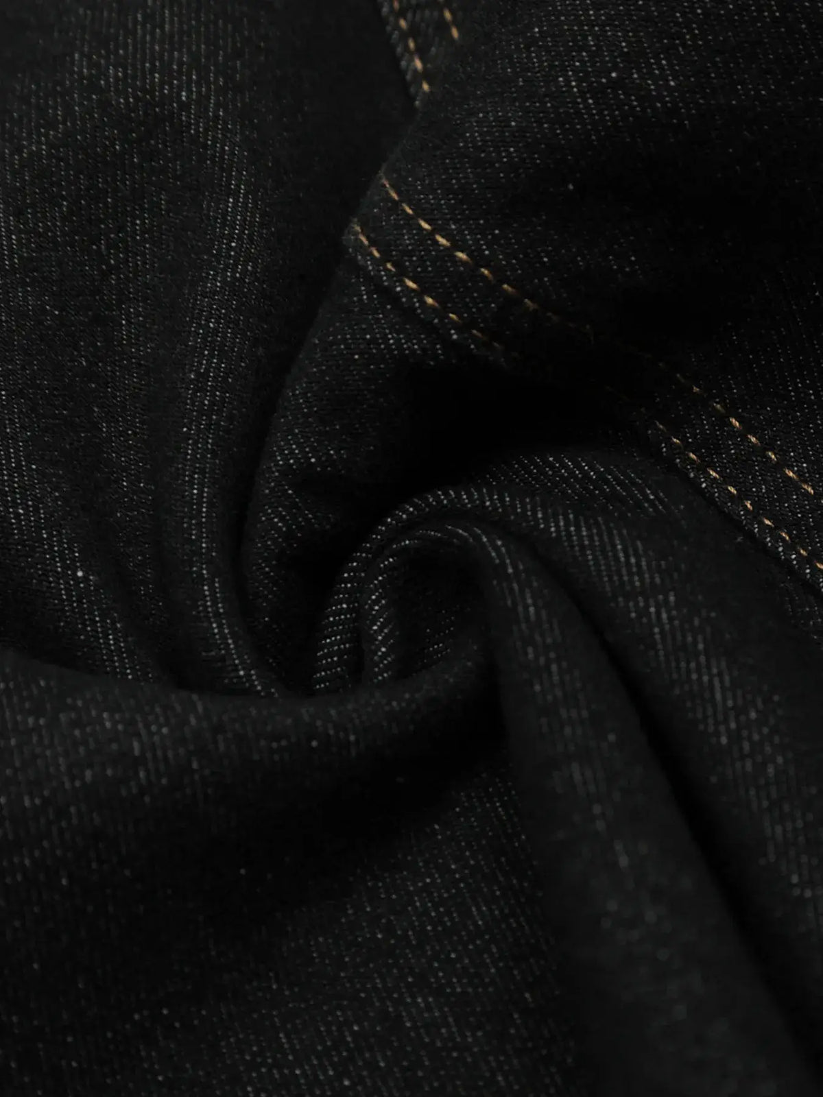 Men's denim shorts fabric close-up in dark indigo with orange contrast stitching