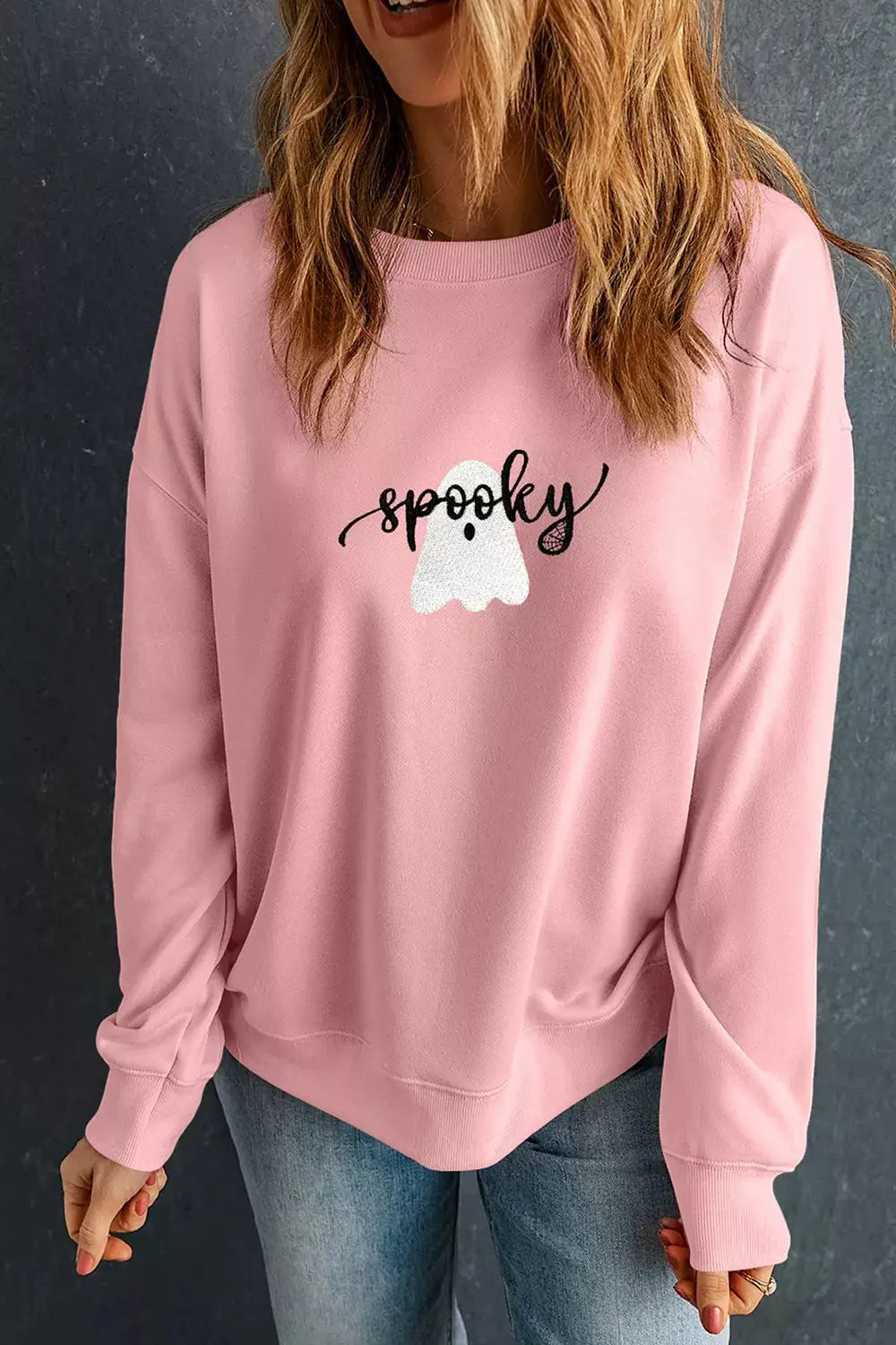 Halloween ghost graphic sweatshirt in pink with round-neck, black spooky script on front, casual fit, fleece fabric.