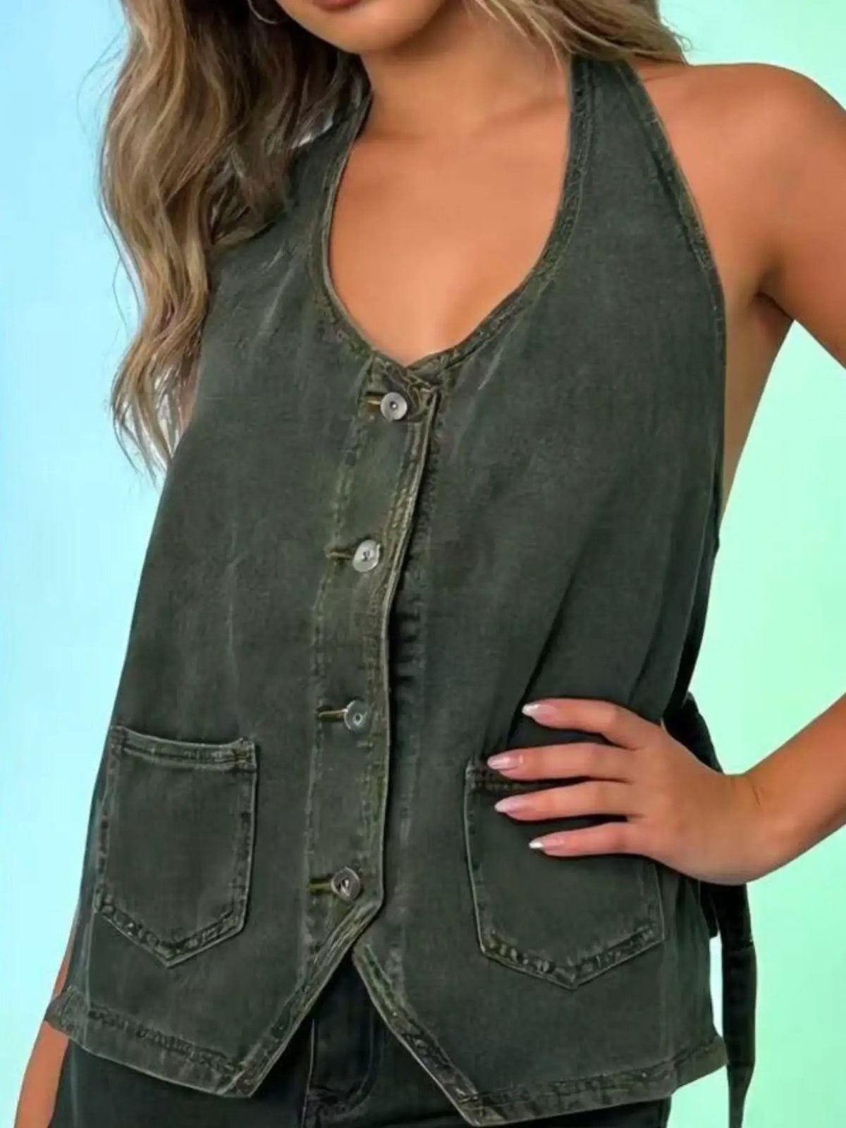 Halter-neck denim vest with button-front closure, adjustable tie, and front pockets in dark wash