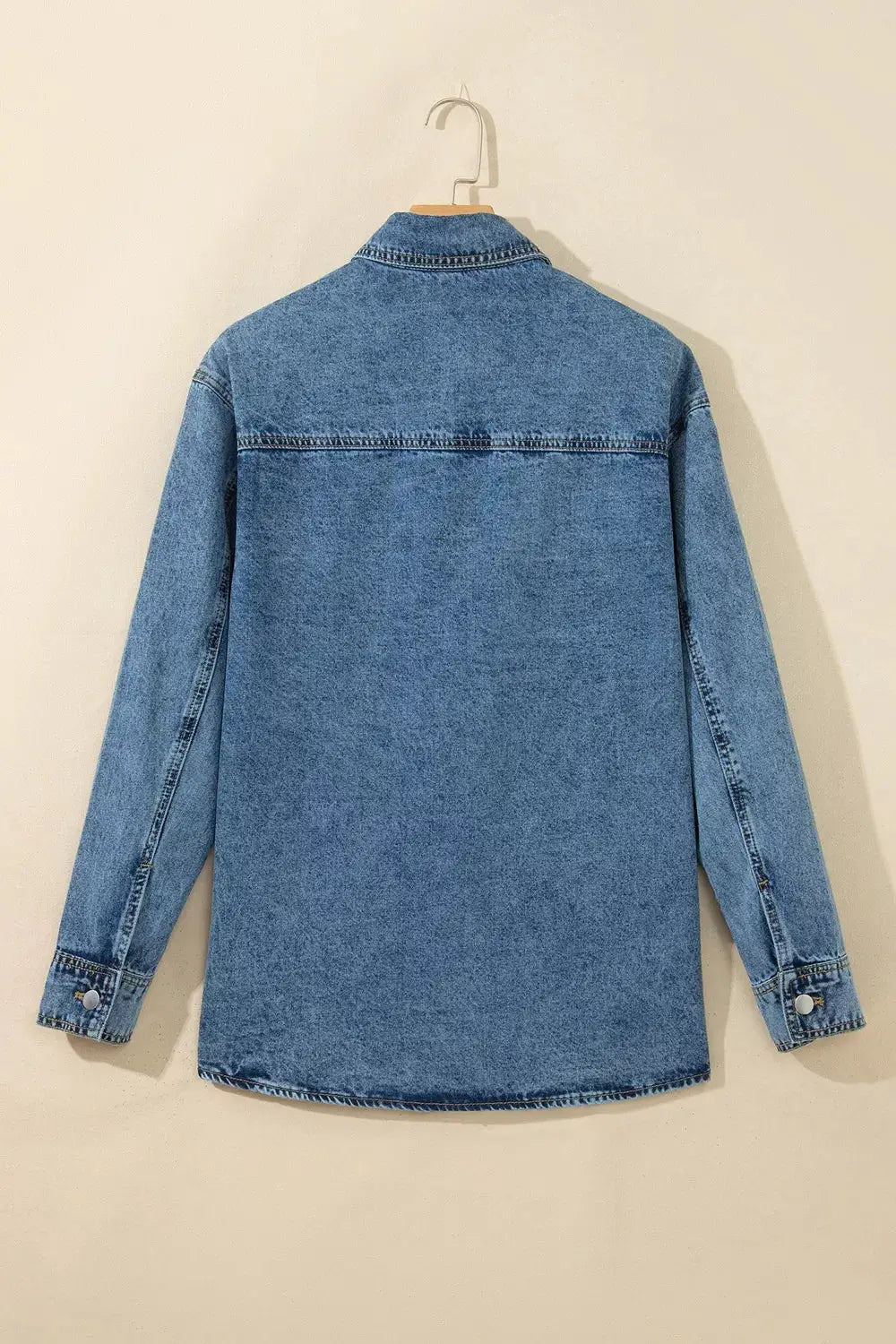 Denim jacket, light-wash blue, long sleeves, hanging on a hanger.