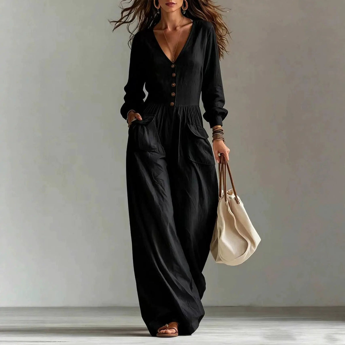 AdTec women's black V-neck long-sleeve jumpsuit with front buttons and pockets, paired with a beige handbag