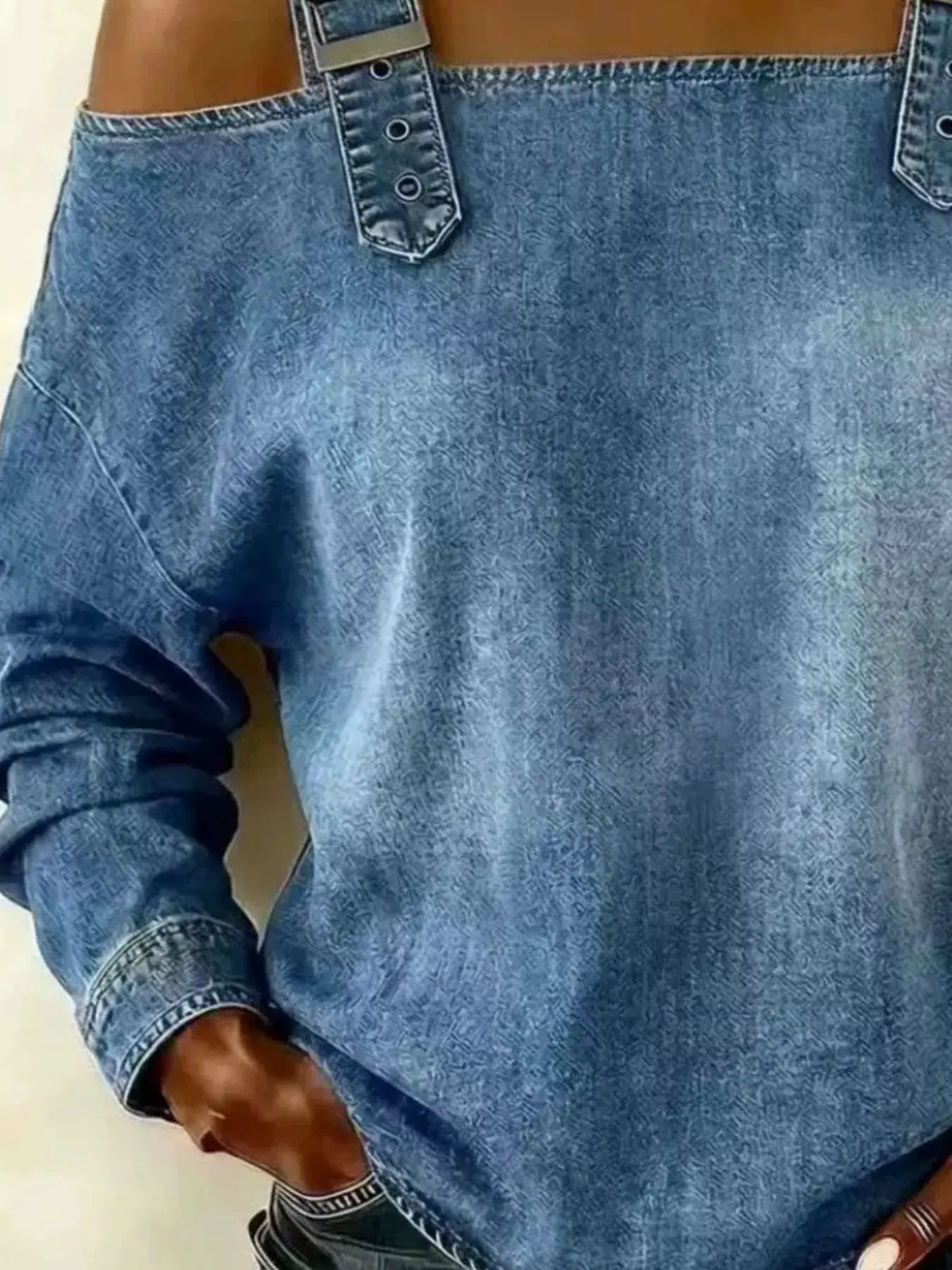 Plus size long sleeve denim top with adjustable buckle straps at shoulders in blue.