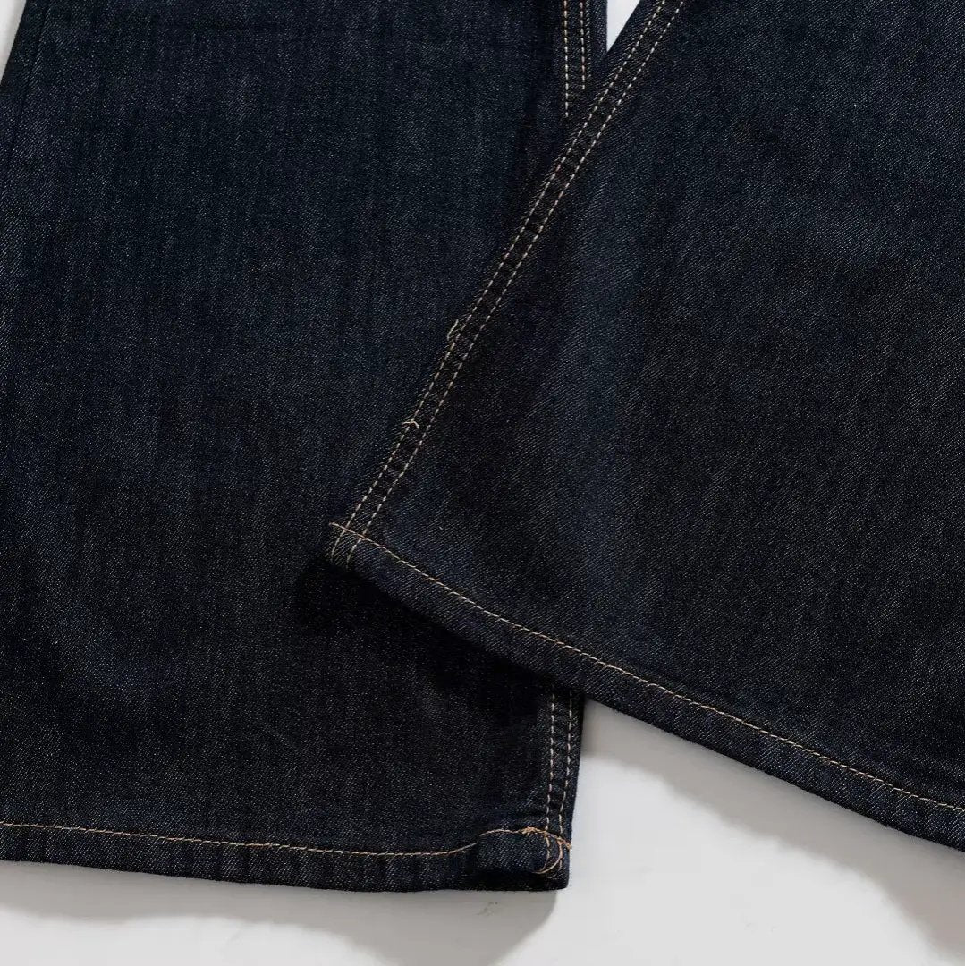 Women's denim flared pants; dark indigo denim with orange contrast stitching at hems.