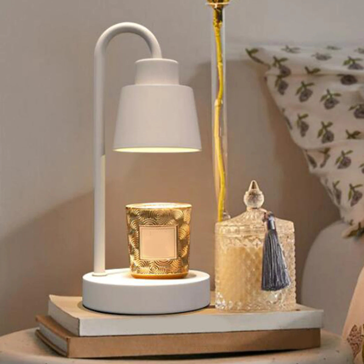 Candle warmer lamp, white, with curved neck and round base on a bedside table.