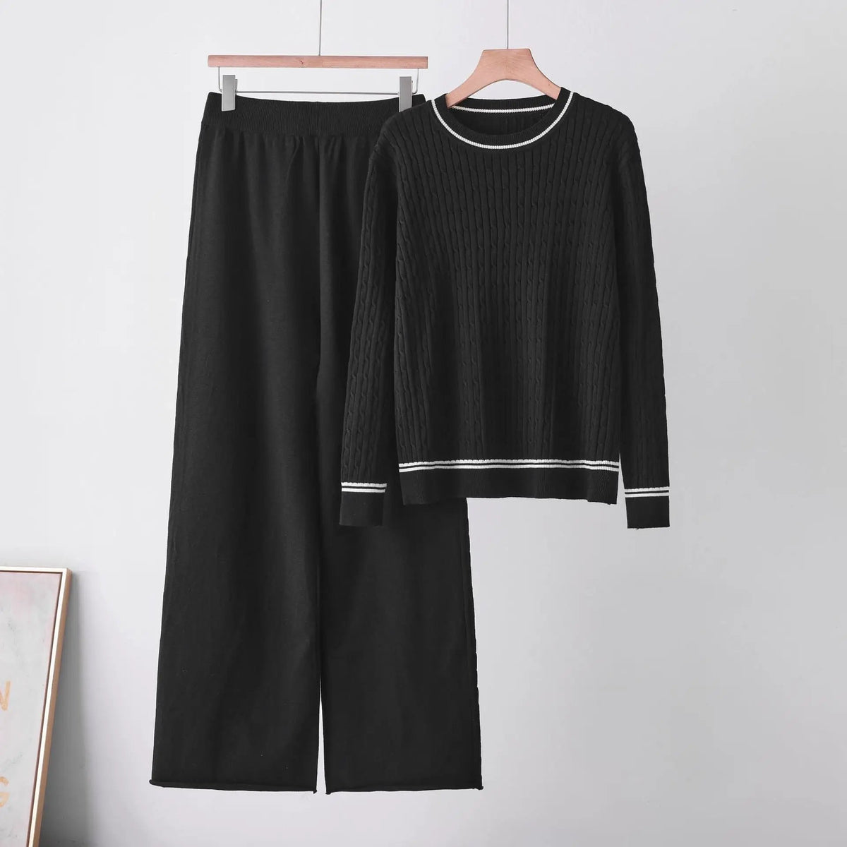 Two-piece black sweater set with round-neck long-sleeve cable-knit top and matching pants