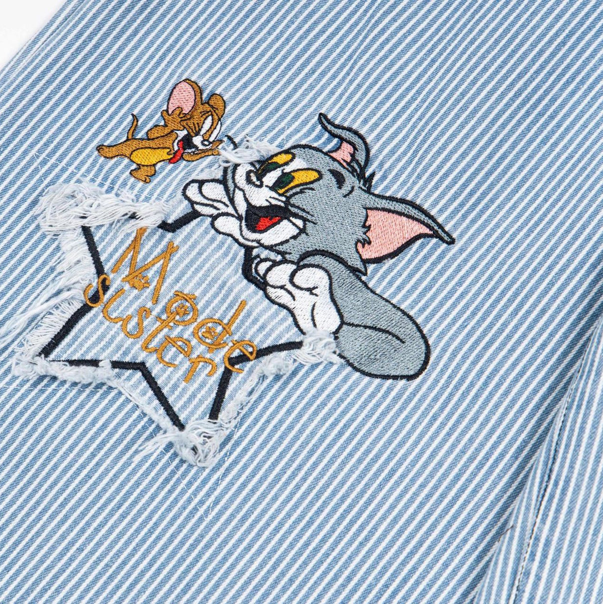 Washed deconstructive striped spliced curved knife jeans, light blue striped denim with cartoon embroidery patch.