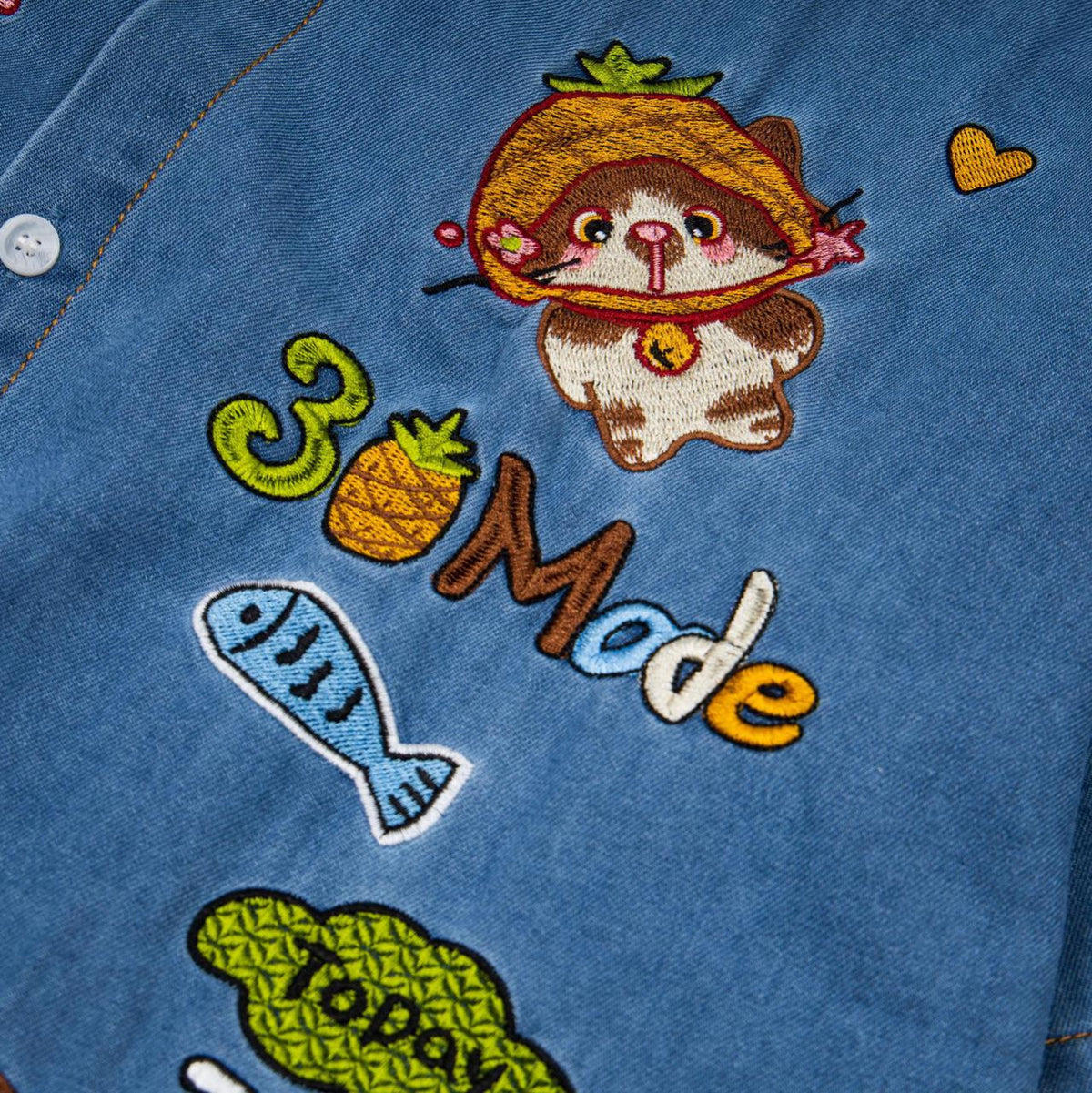 Pineapple cat embroidered blue denim shirt with colorful fruit and fish motifs.