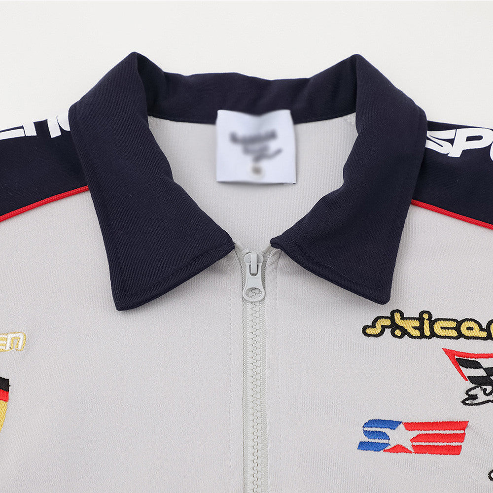 Letter color-block zip polo shirt with navy collar on light gray fabric; street-style embroidered patches