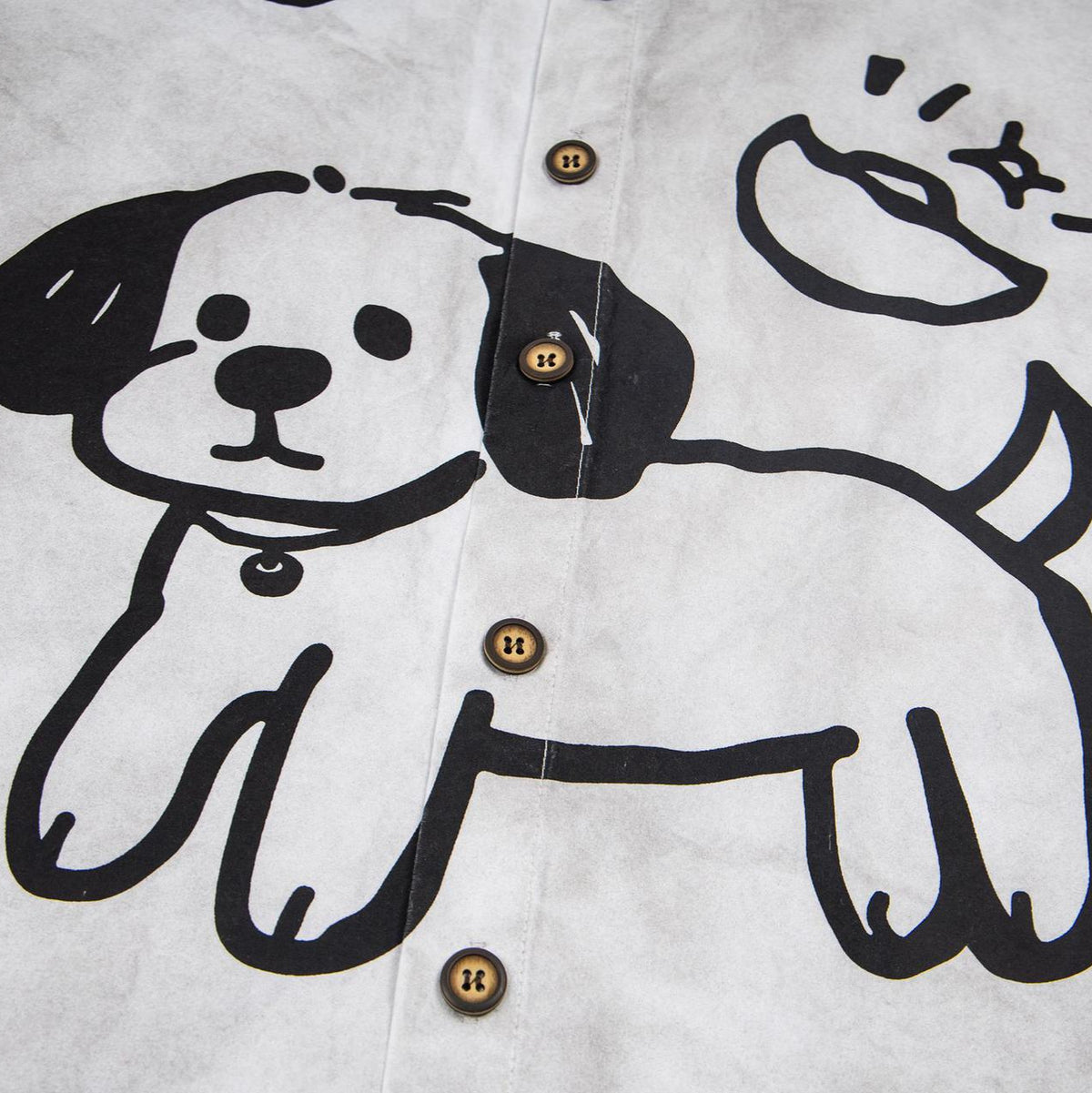 Graphic T-shirt featuring a graffiti puppy illustration on light gray fabric with brown buttons.