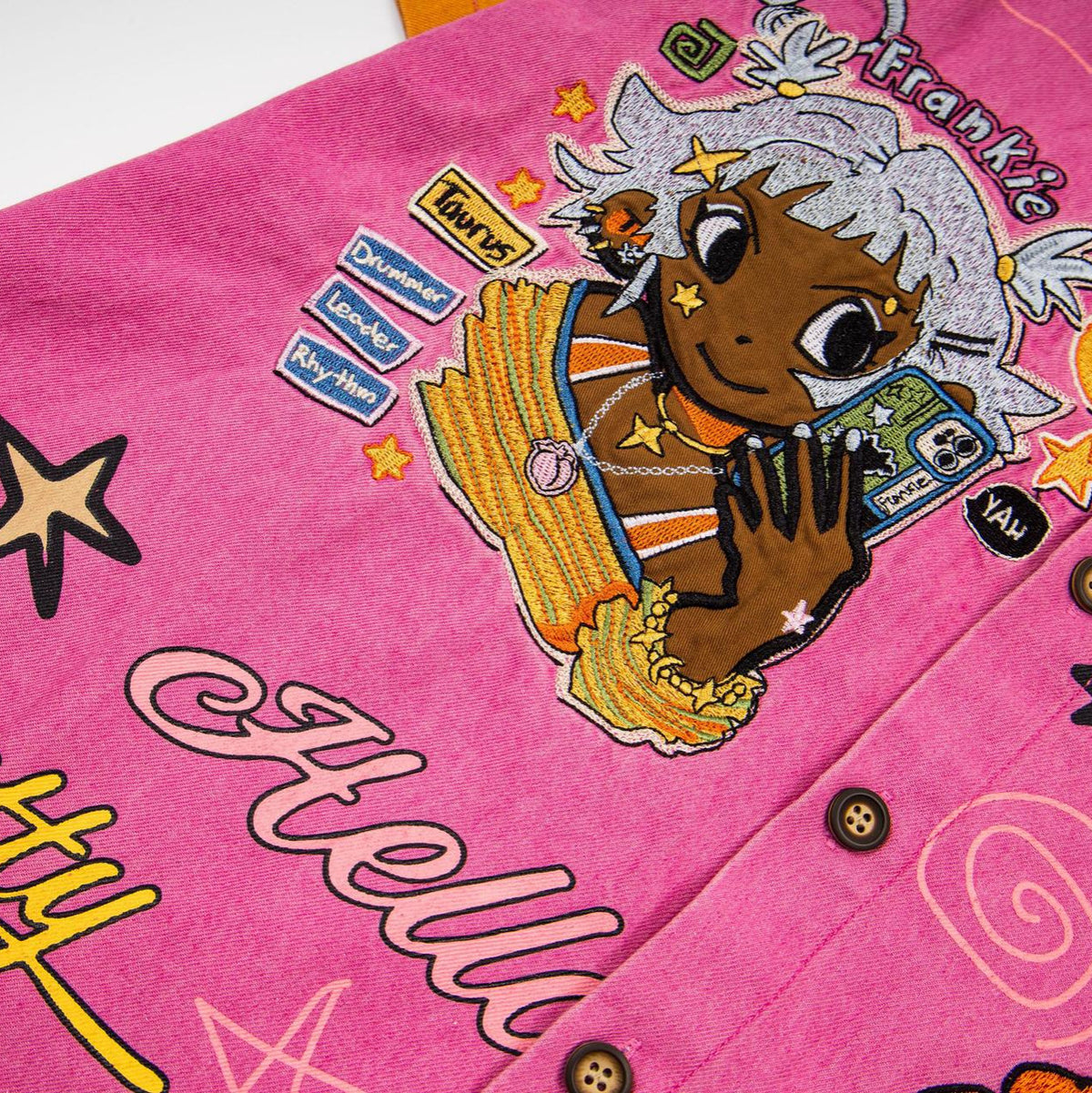 Embroidered pink short-sleeve shirt with patchwork cartoon of a Black-skinned girl and street-style graphics.