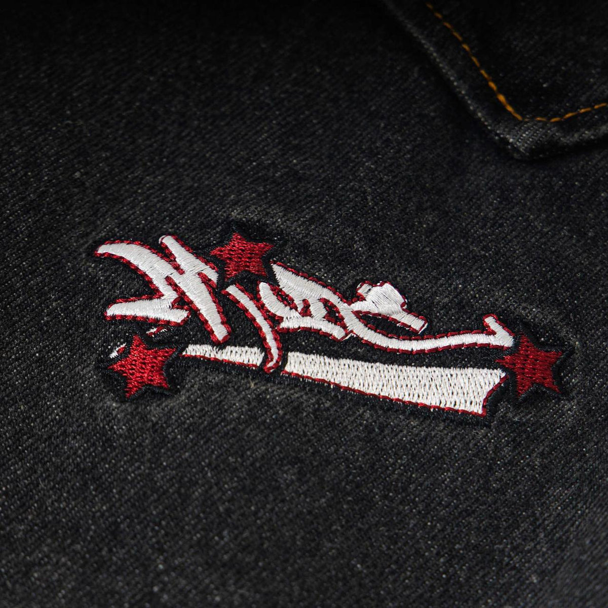 Loose workwear jeans in dark denim with an embroidered red stars patch and white lettering