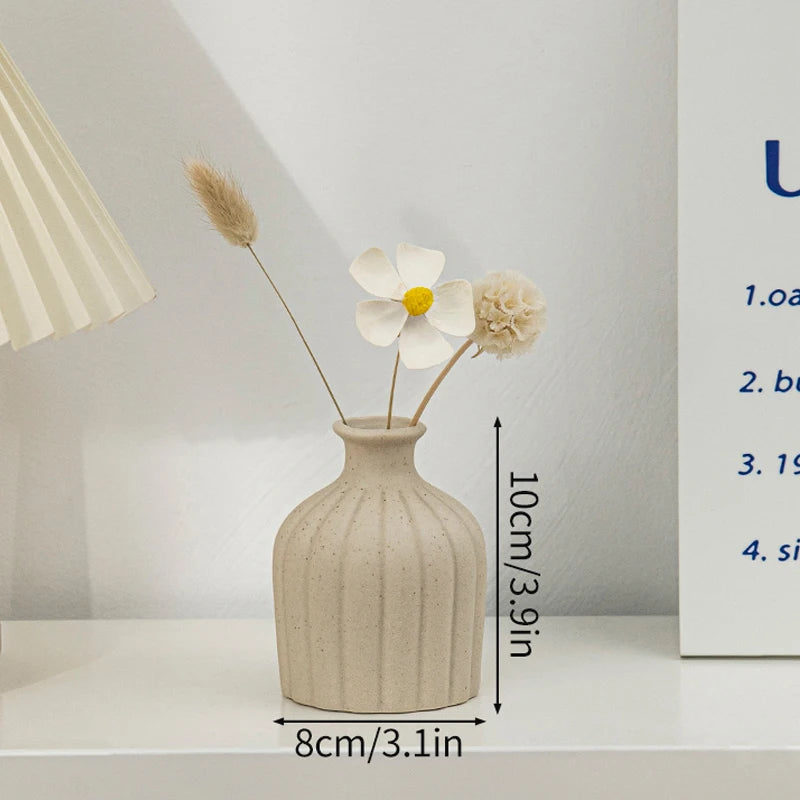 Beige ribbed ceramic flower vase with dried stems, 8 cm wide by 10 cm tall.