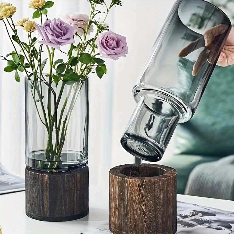 Glass vase on a dark wooden base for hydroponic plants; modern tabletop floral display.