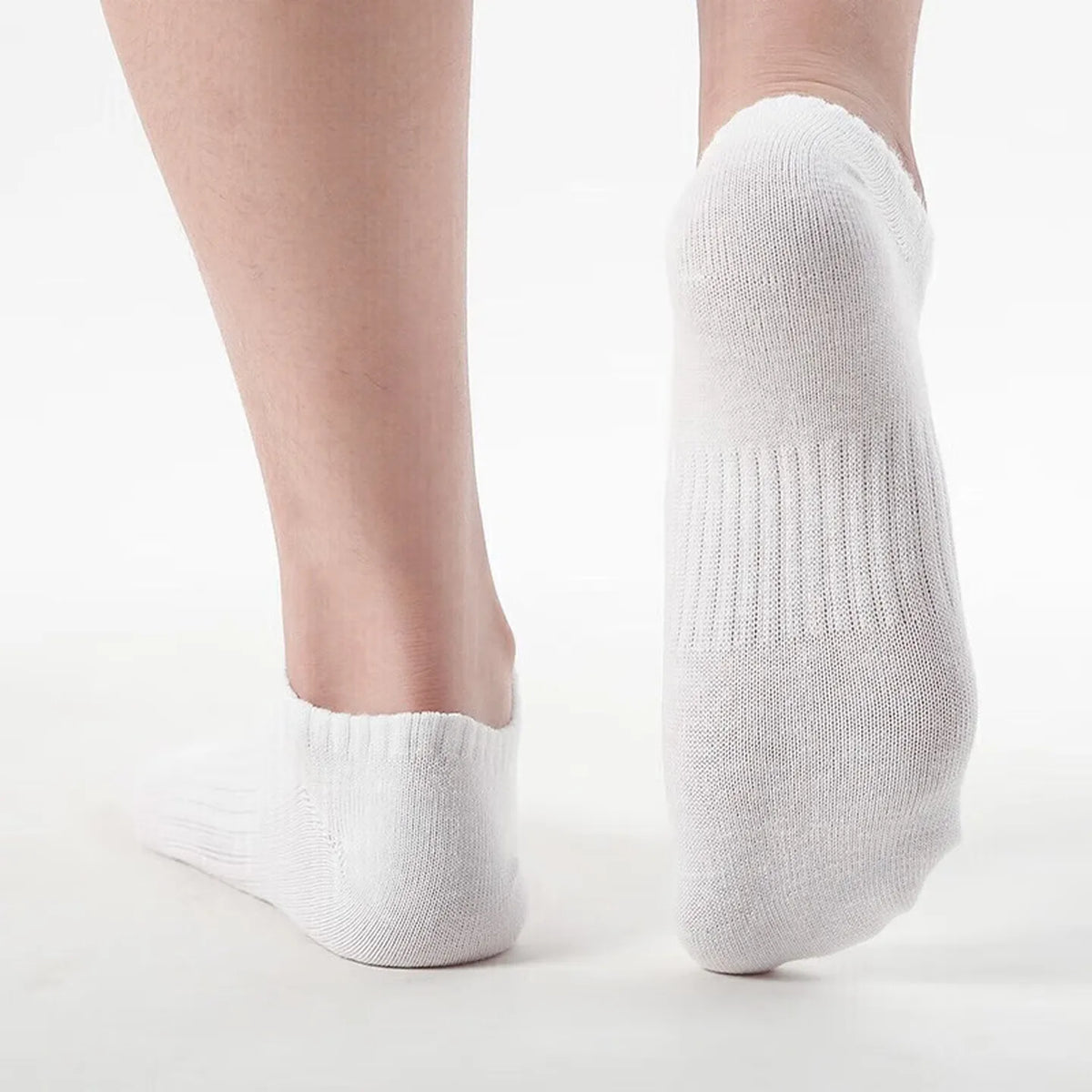 Pair of white short-cuff basketball socks on feet; knit fabric with ribbed cuffs.