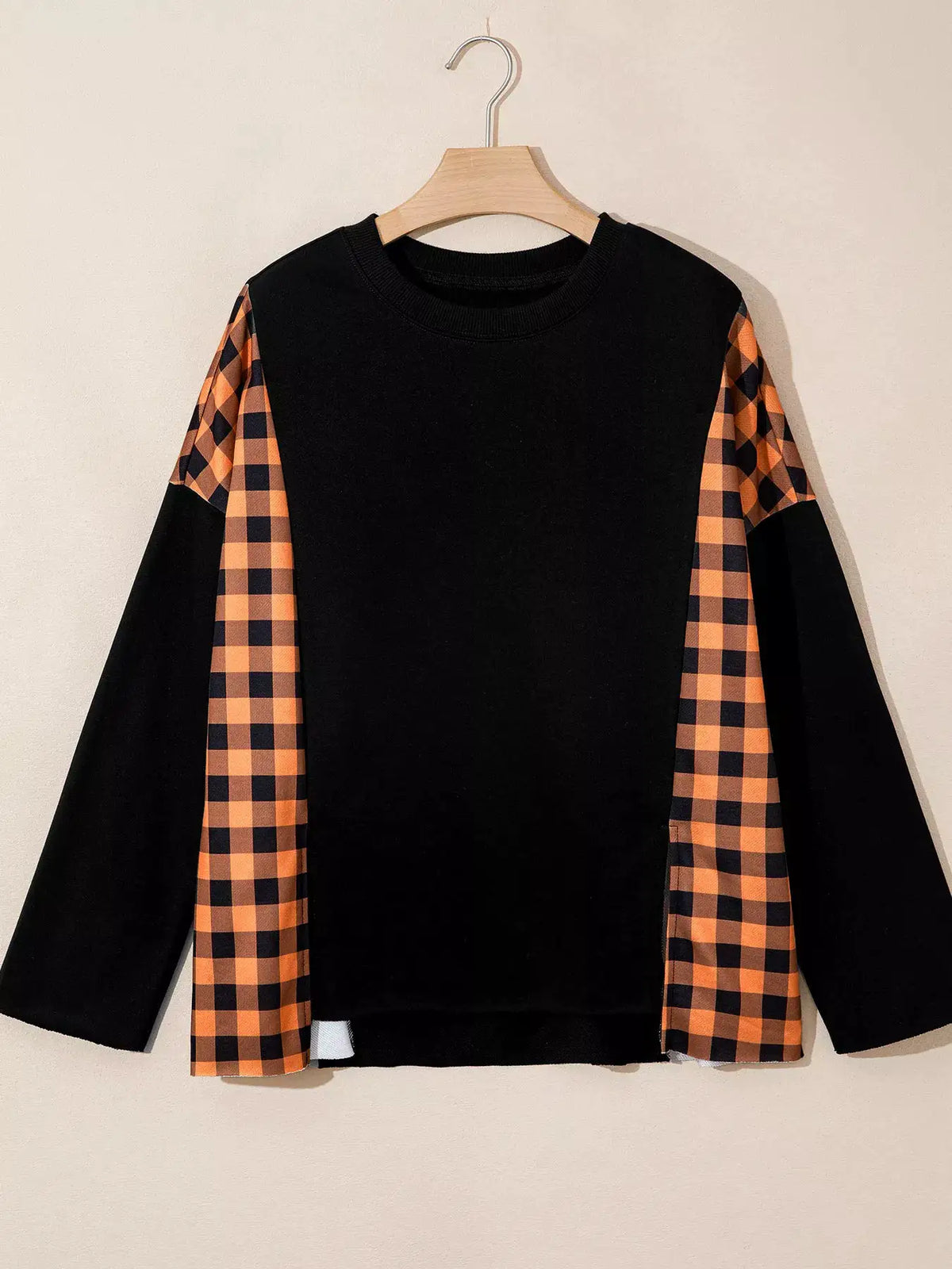 Patchwork plaid long-sleeve top with black body and orange plaid side panels.