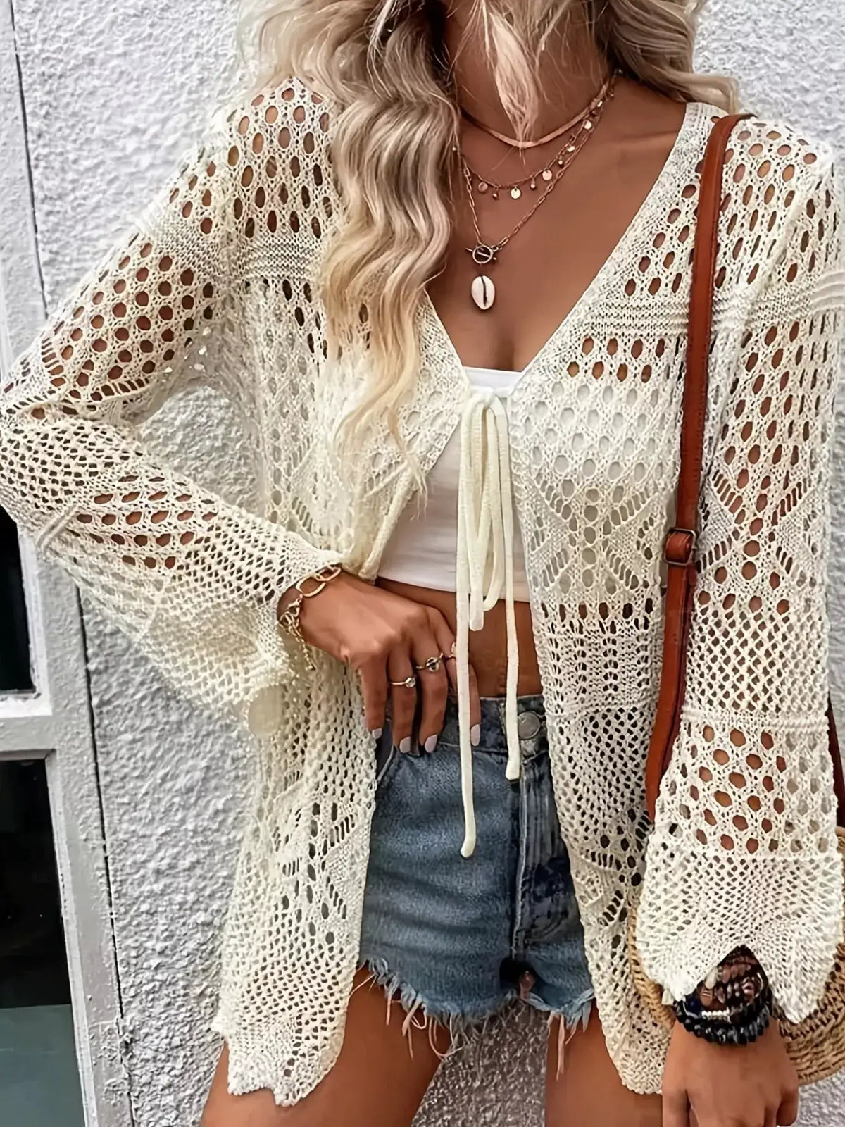 Lightweight crochet tie-front cardigan in cream worn over a white top with denim shorts.