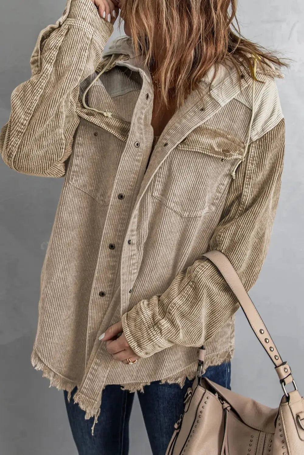 Snap-front hooded corduroy shacket in beige, with frayed hem and chest pockets.