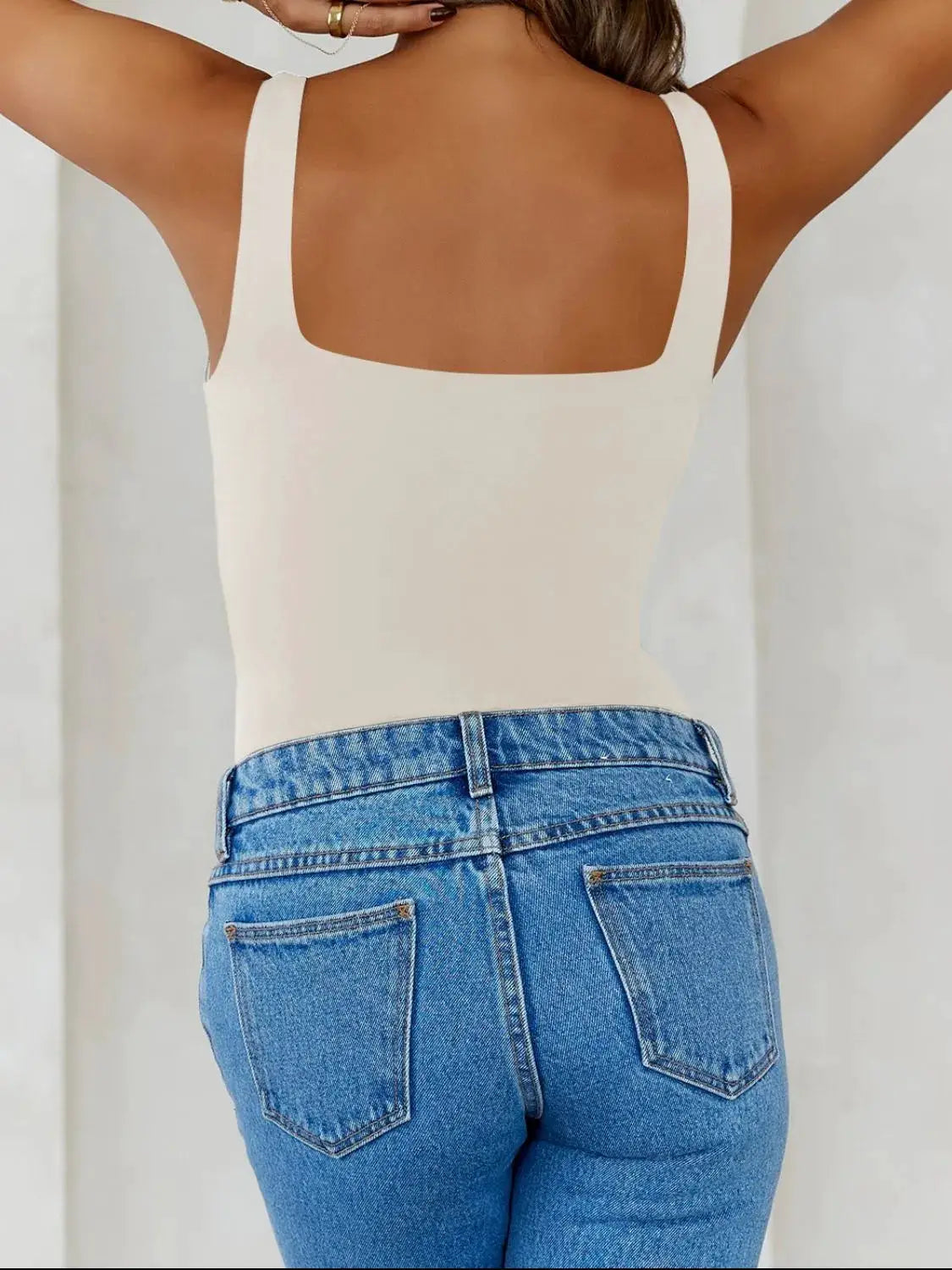 Solid color wide-strap cami in cream, back view with square neckline, paired with blue jeans